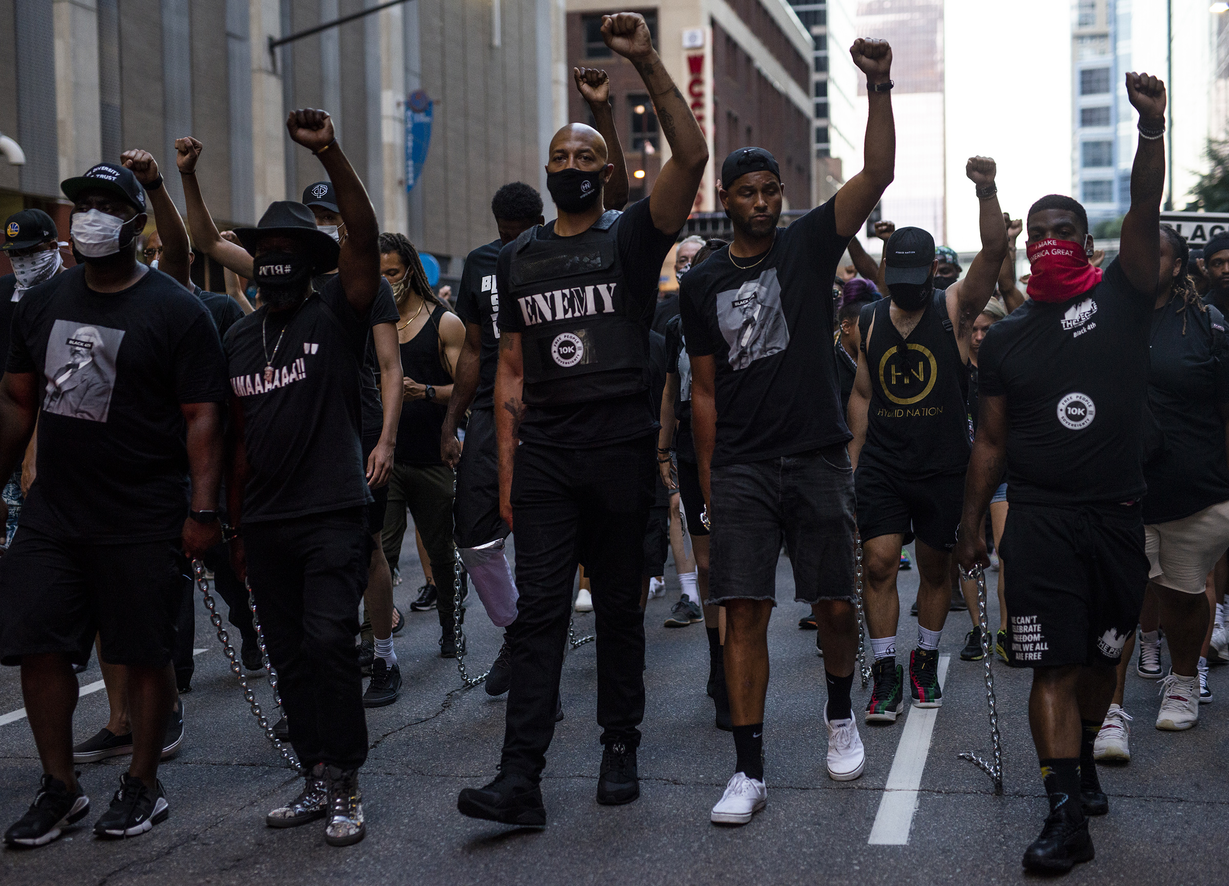 Royce White, center, and demonstrators drag chains behind them during the Black 4th protest in downtown Minneapolis on July 4
