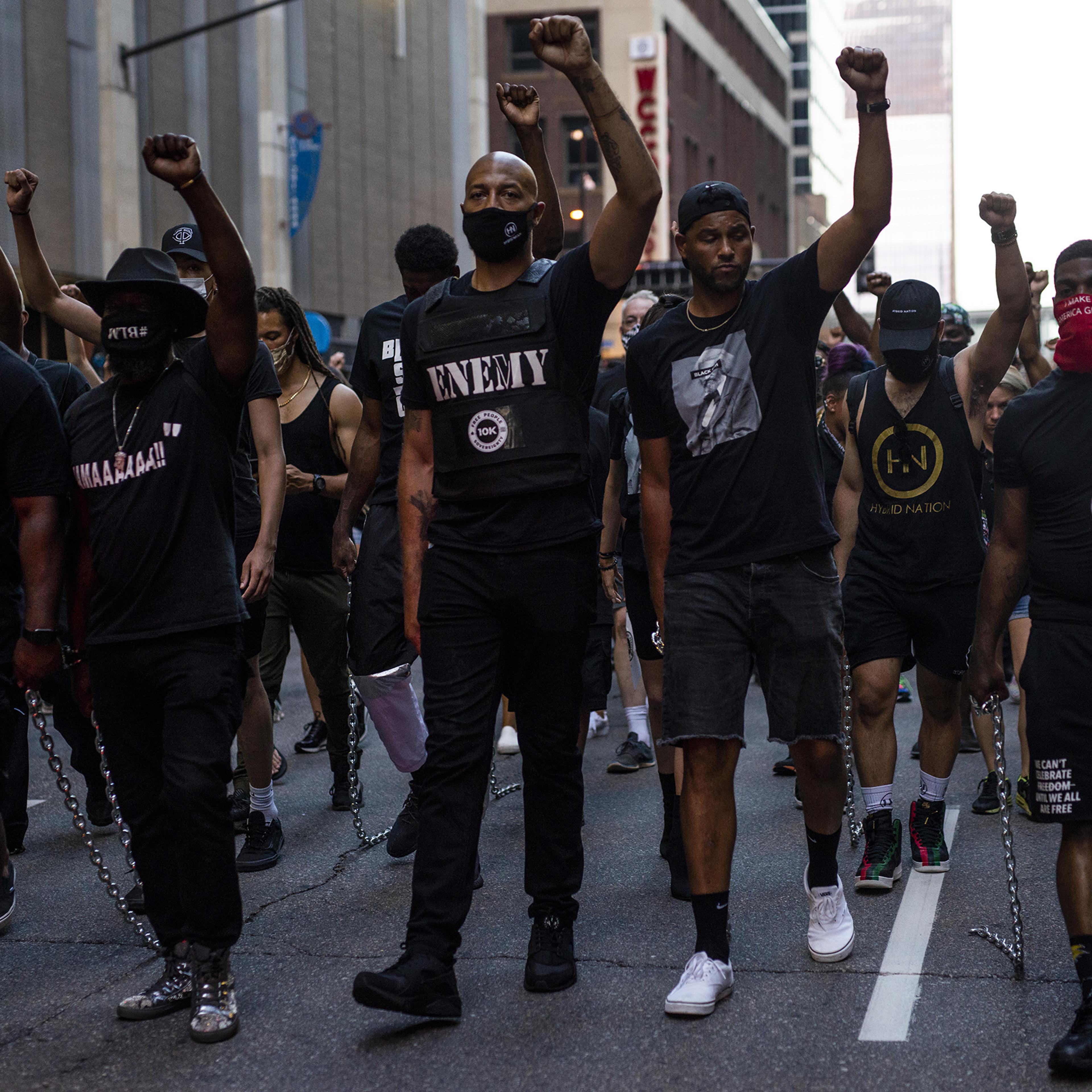 Royce White, center, and demonstrators drag chains behind them during the Black 4th protest in downtown Minneapolis on July 4