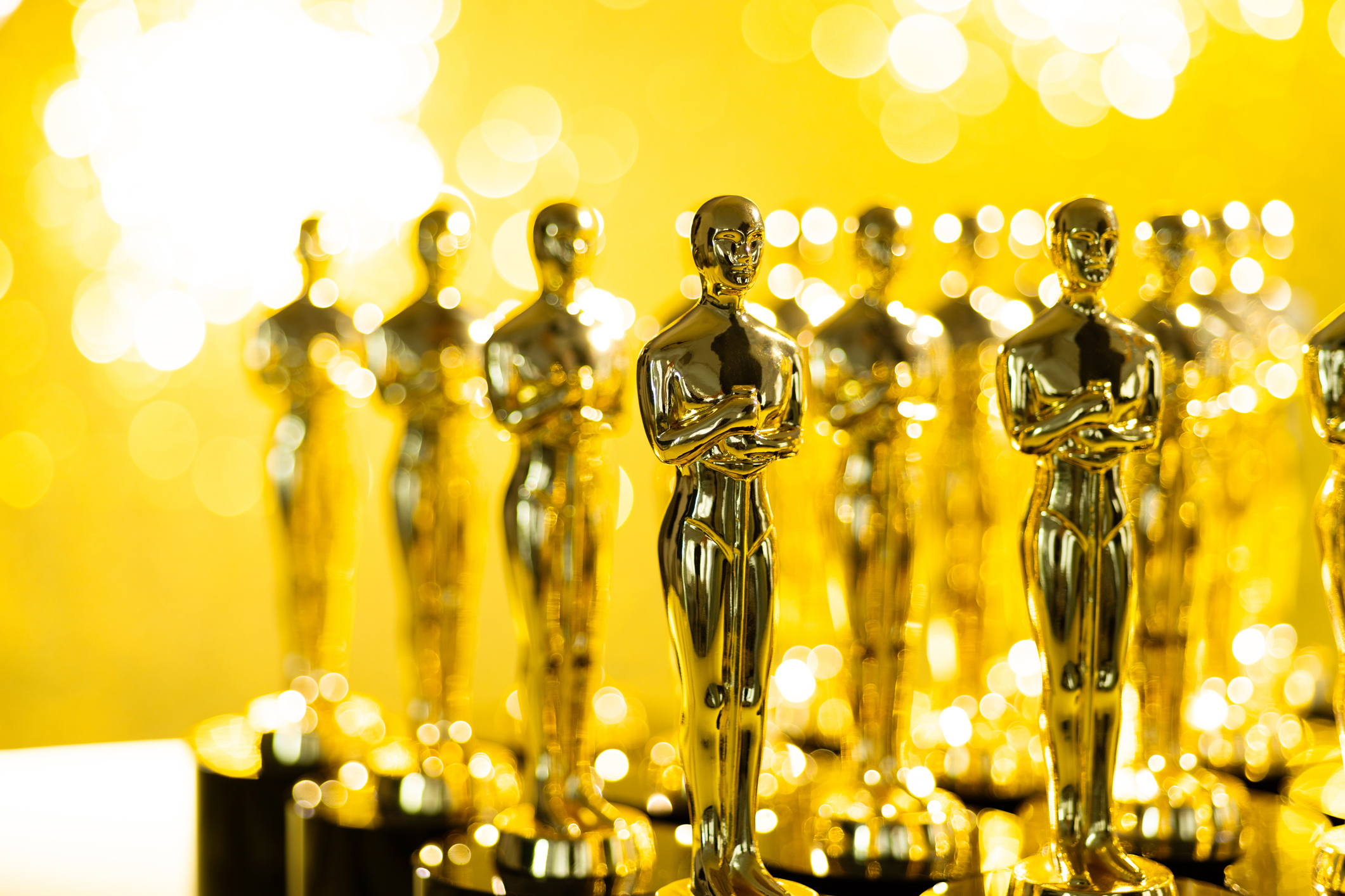Group of golden statuette on shiny yellow background