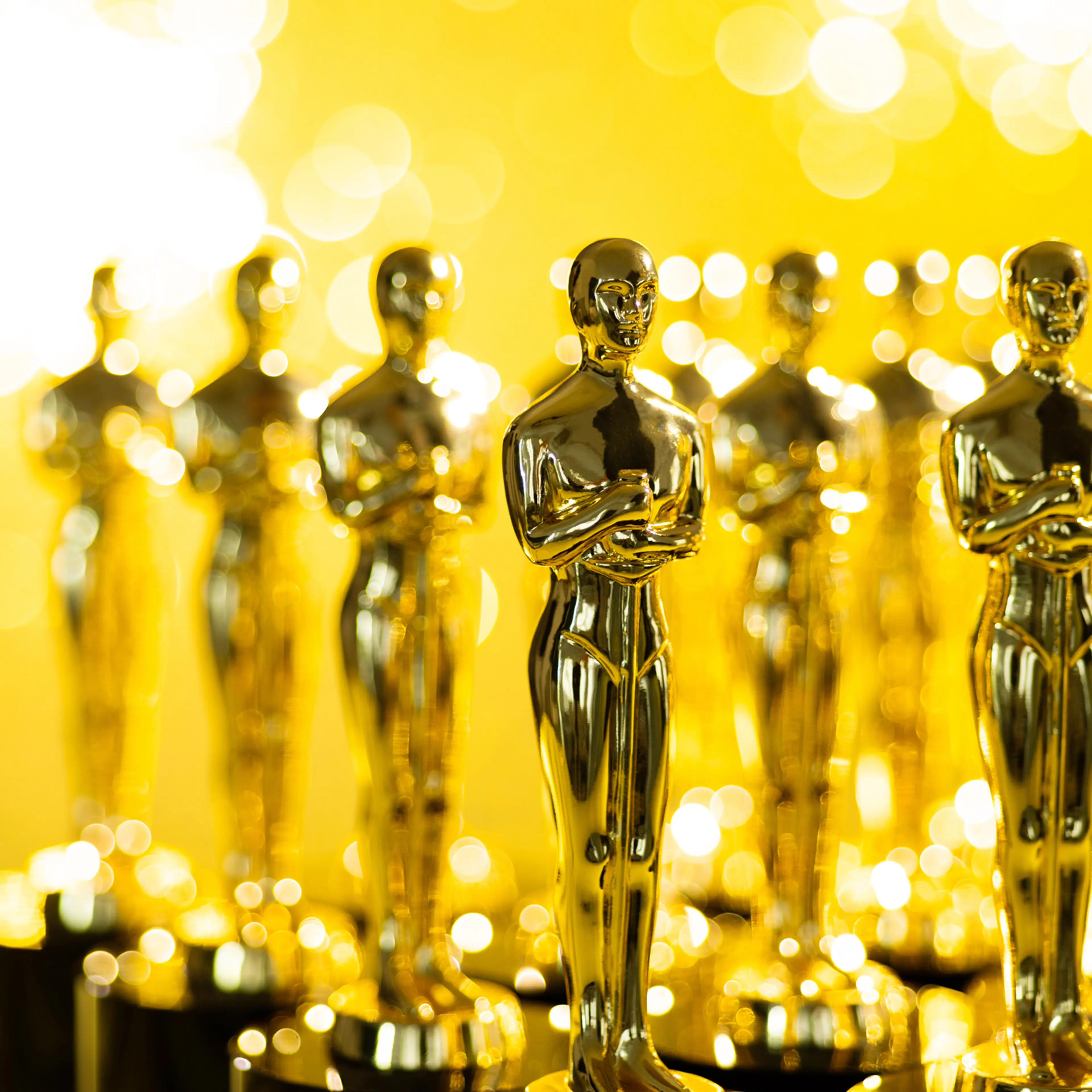 Group of golden statuette on shiny yellow background