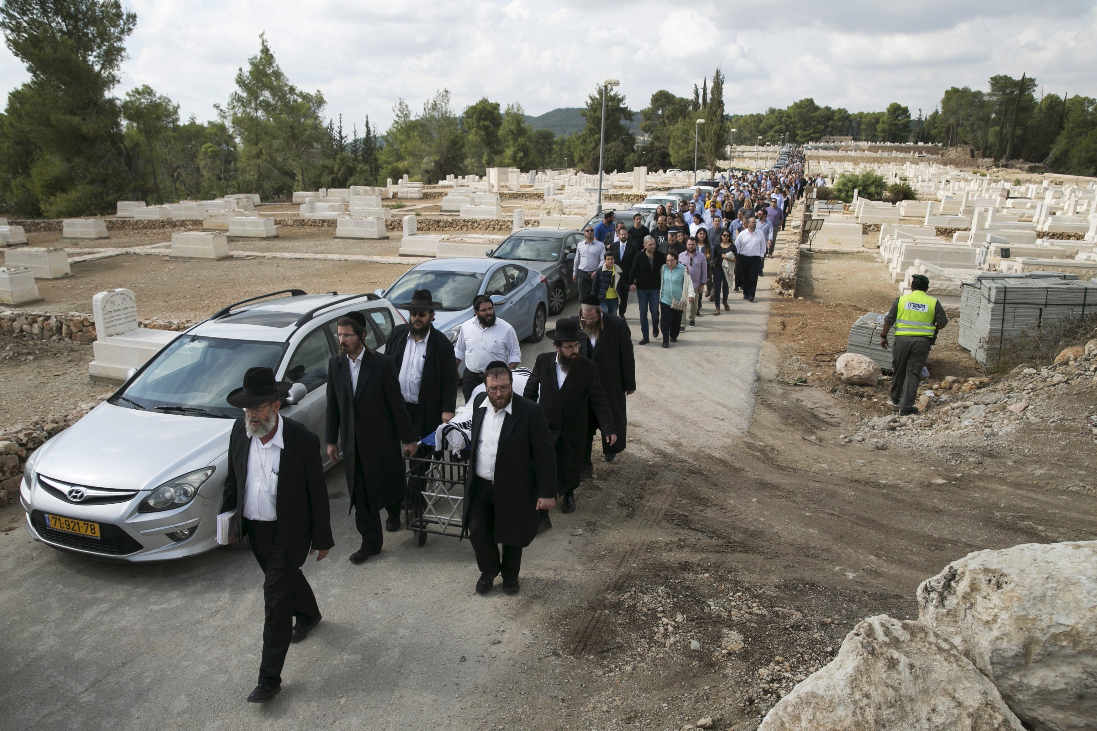 Friends and family walk behind ultra-Orthodox Jewish men as they wheel the body of American-Israeli Lakin, during his funeral in Beit Shemesh,