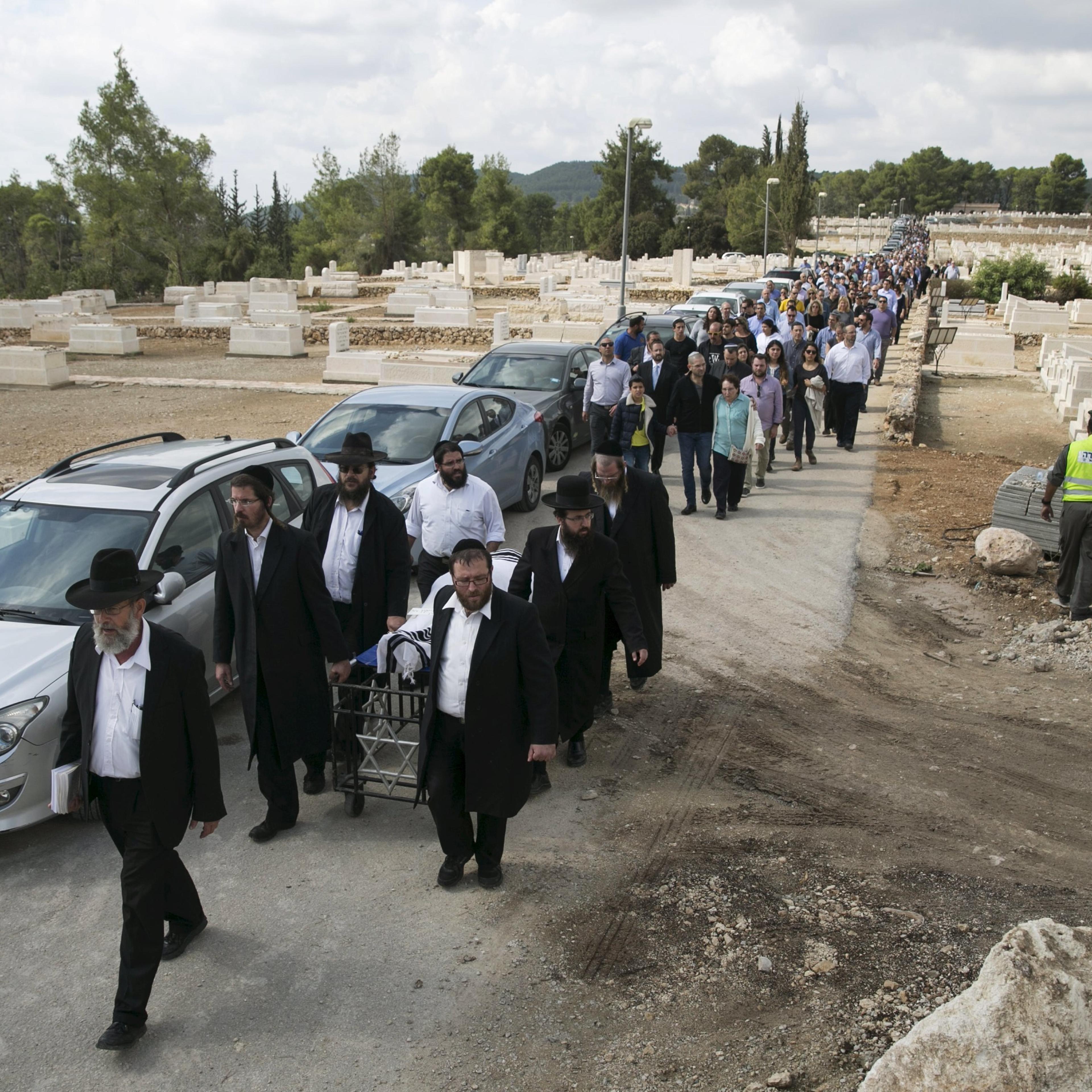 Friends and family walk behind ultra-Orthodox Jewish men as they wheel the body of American-Israeli Lakin, during his funeral in Beit Shemesh,