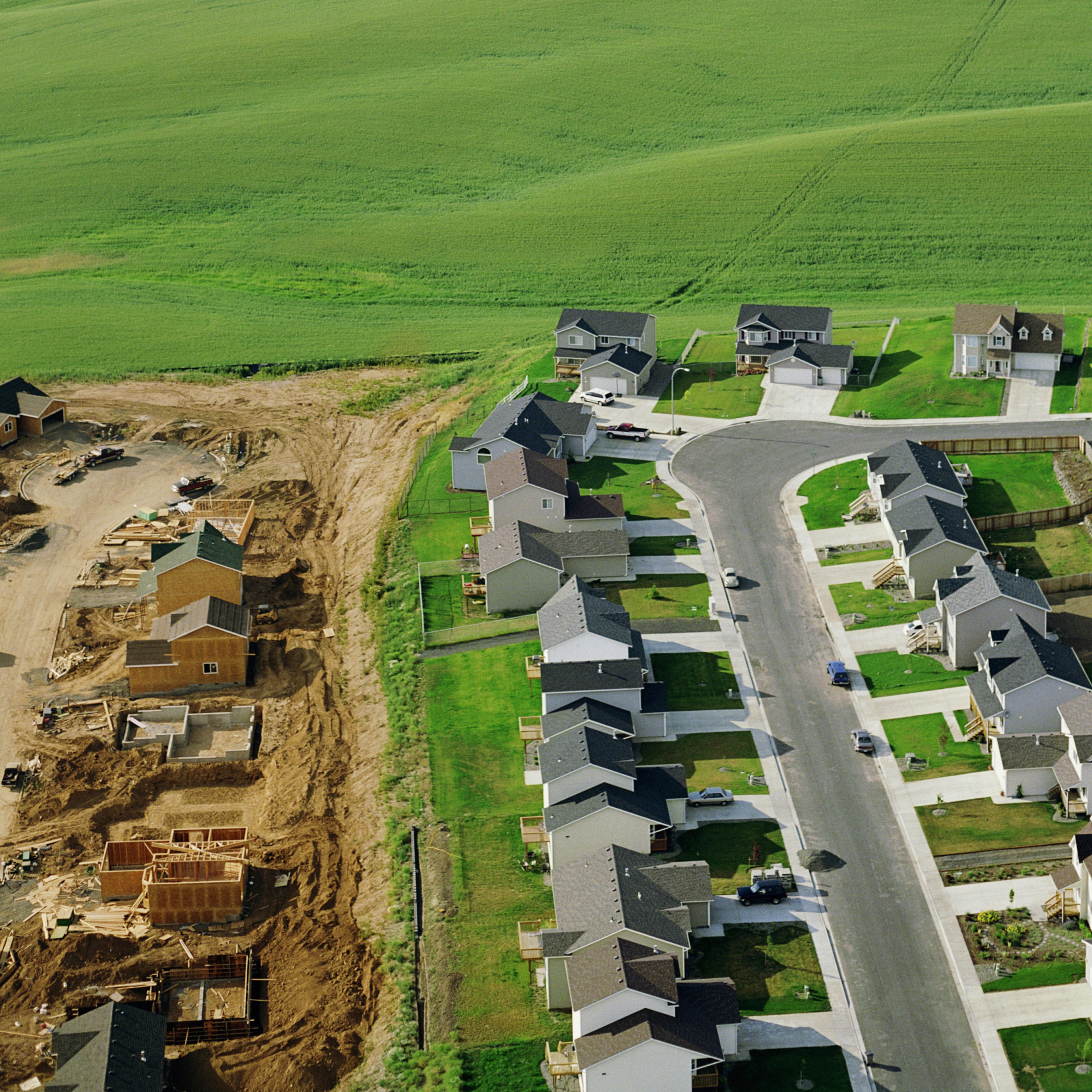 Housing development under construction on farmland, aerial view.