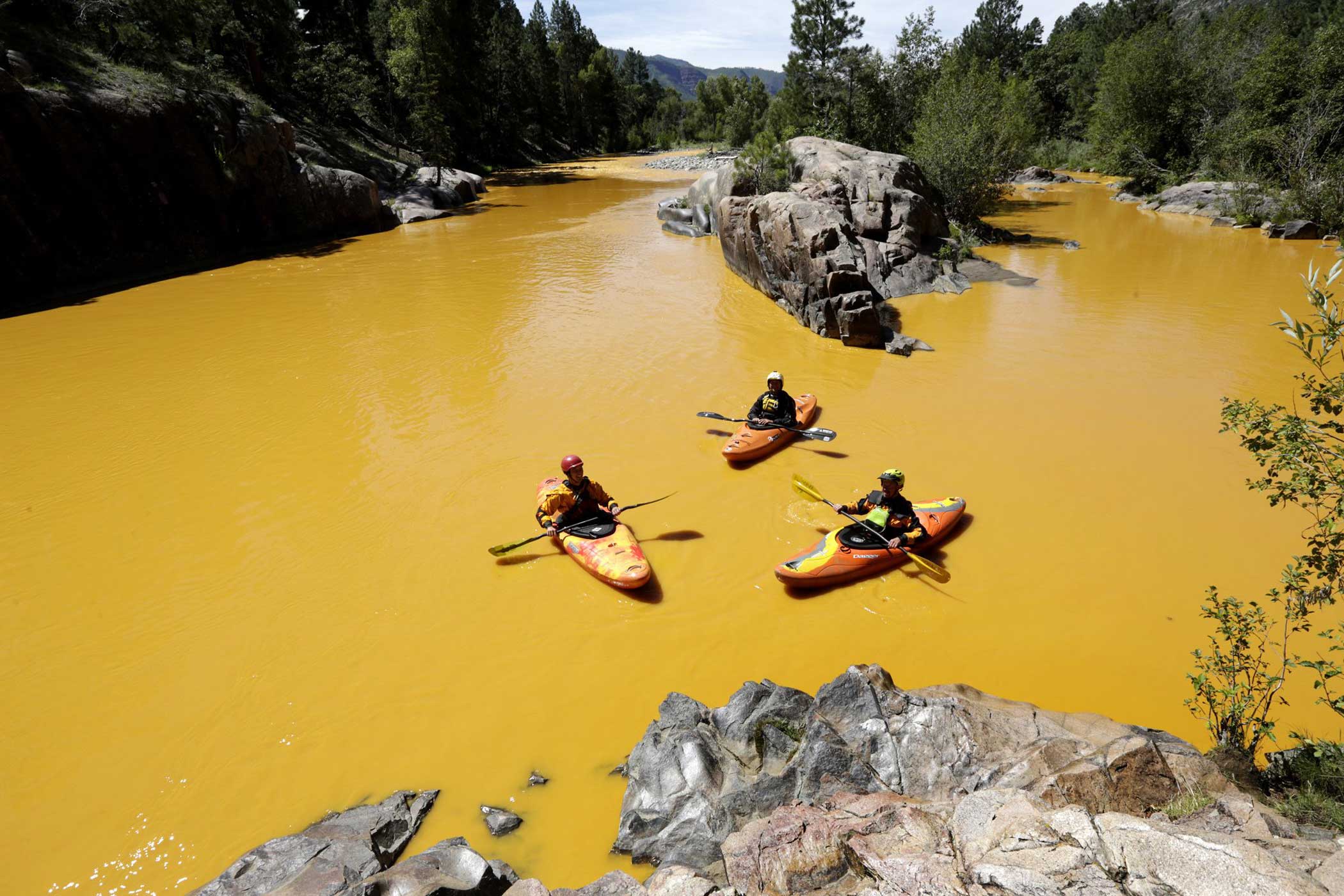 People kayak in the Animas River near Durango, Colo., in water colored from a mine waste spill.