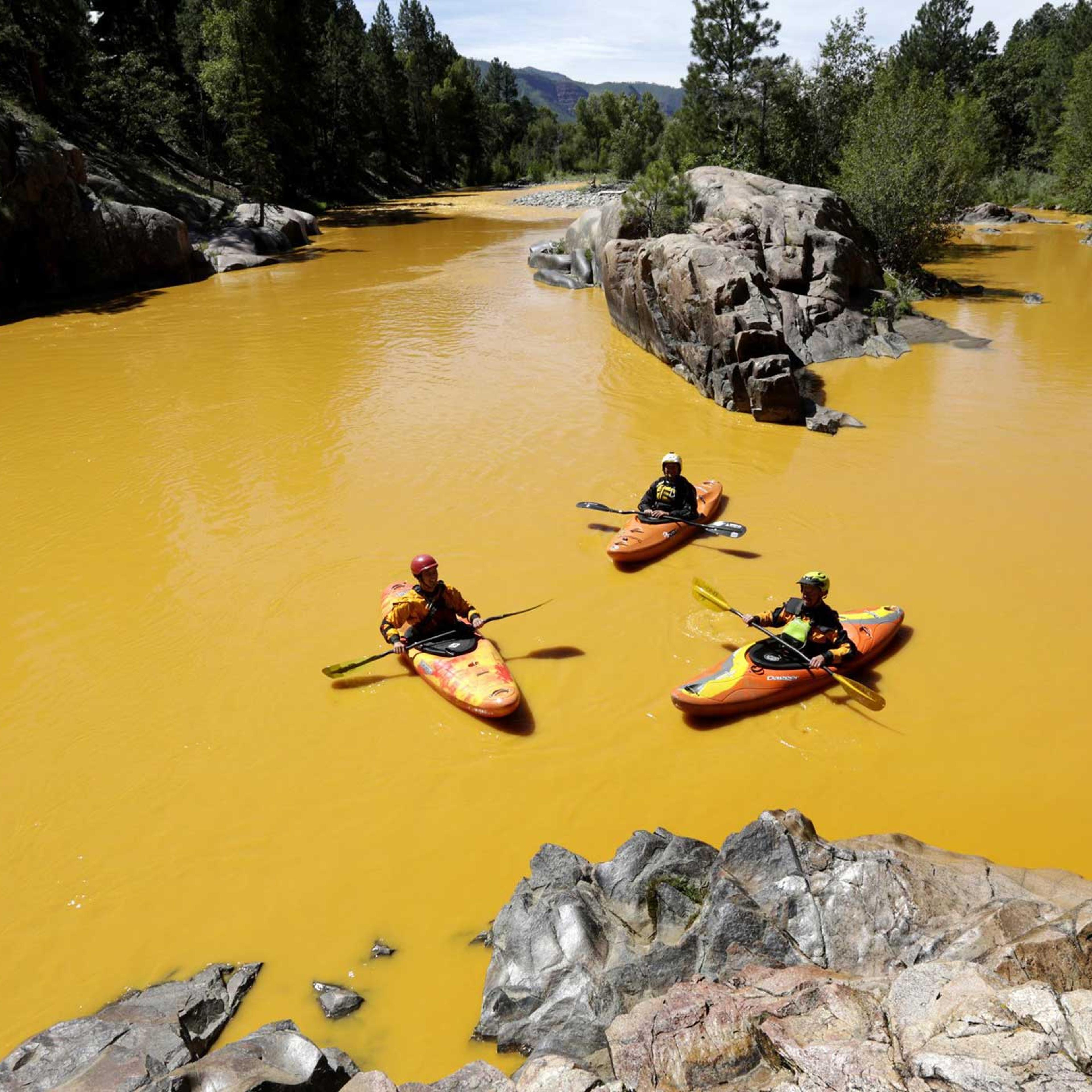 People kayak in the Animas River near Durango, Colo., in water colored from a mine waste spill.
