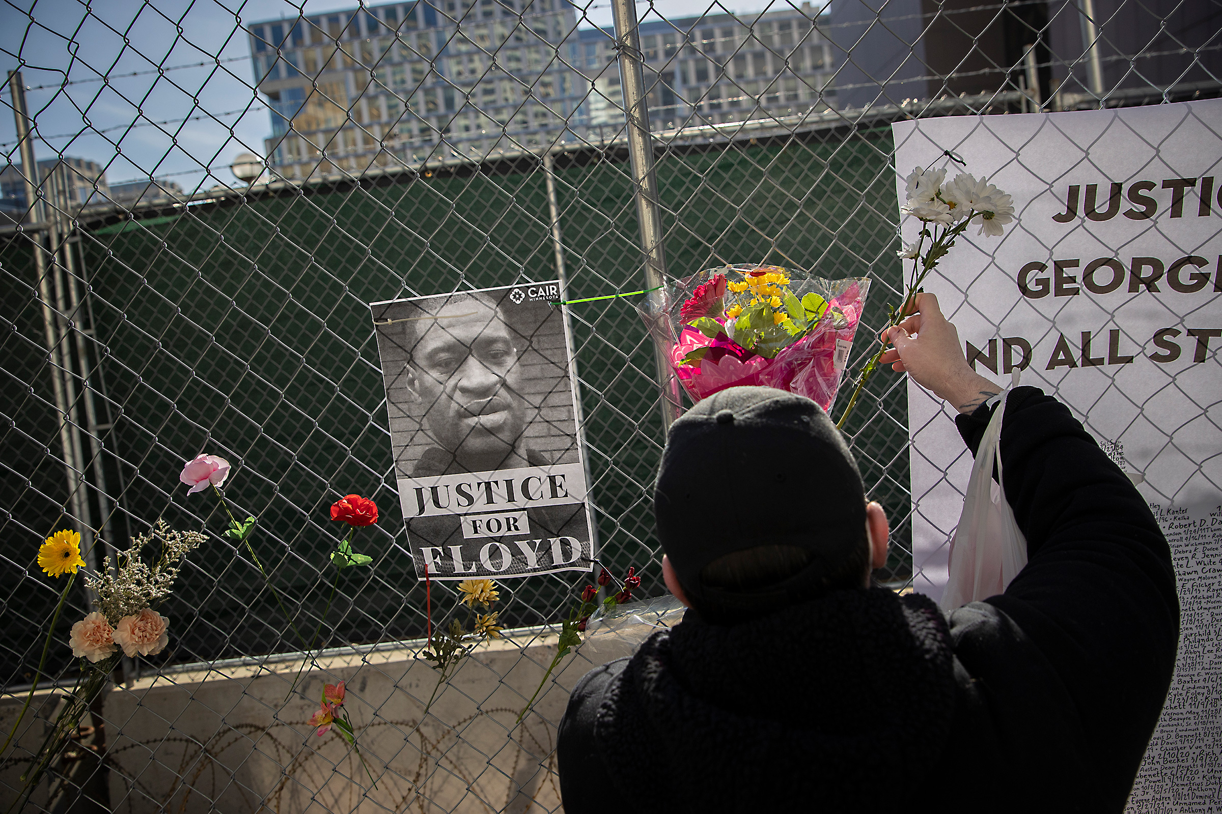 Patrick Fisher adds flowers to a fence around the building housing the Hennepin County court
