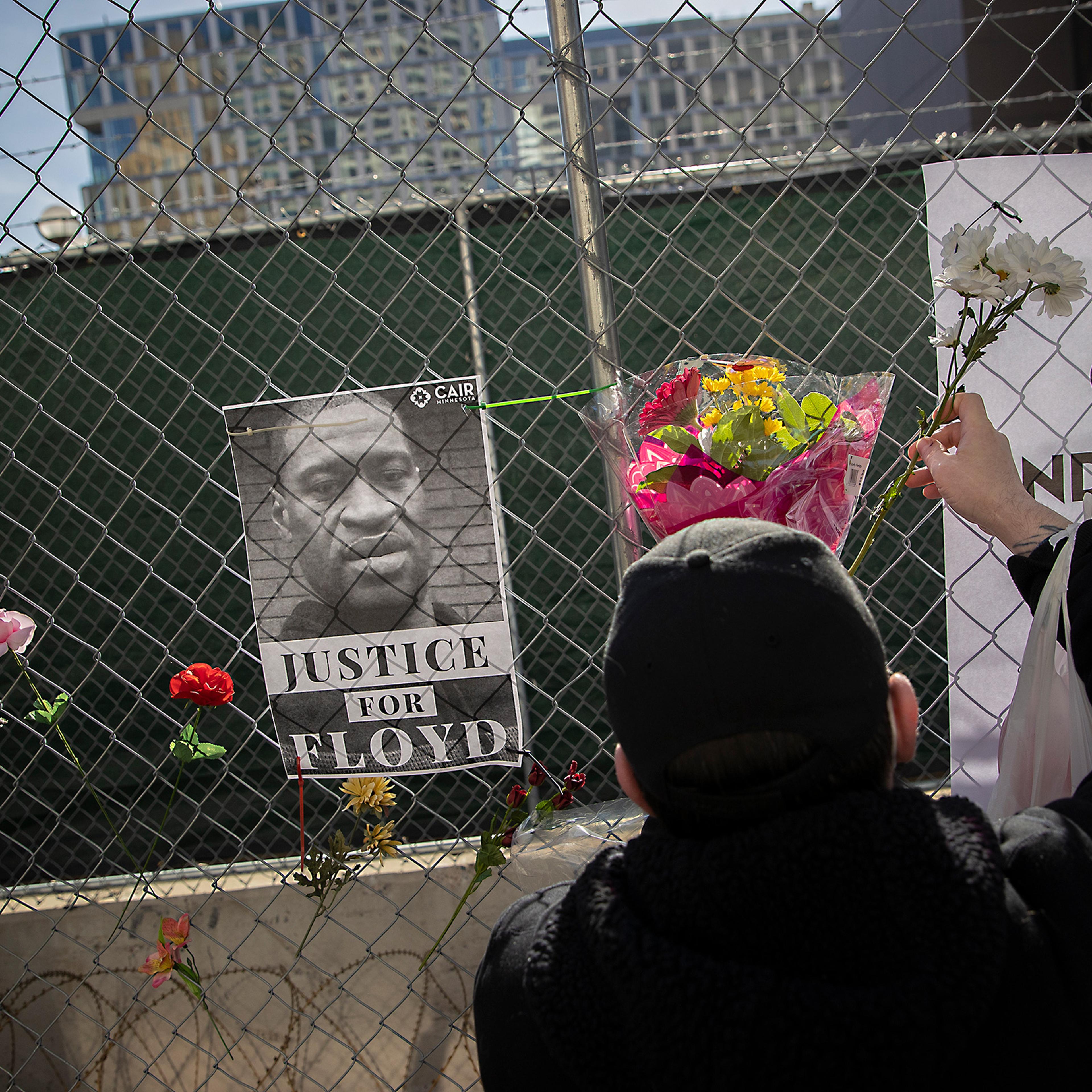 Patrick Fisher adds flowers to a fence around the building housing the Hennepin County court