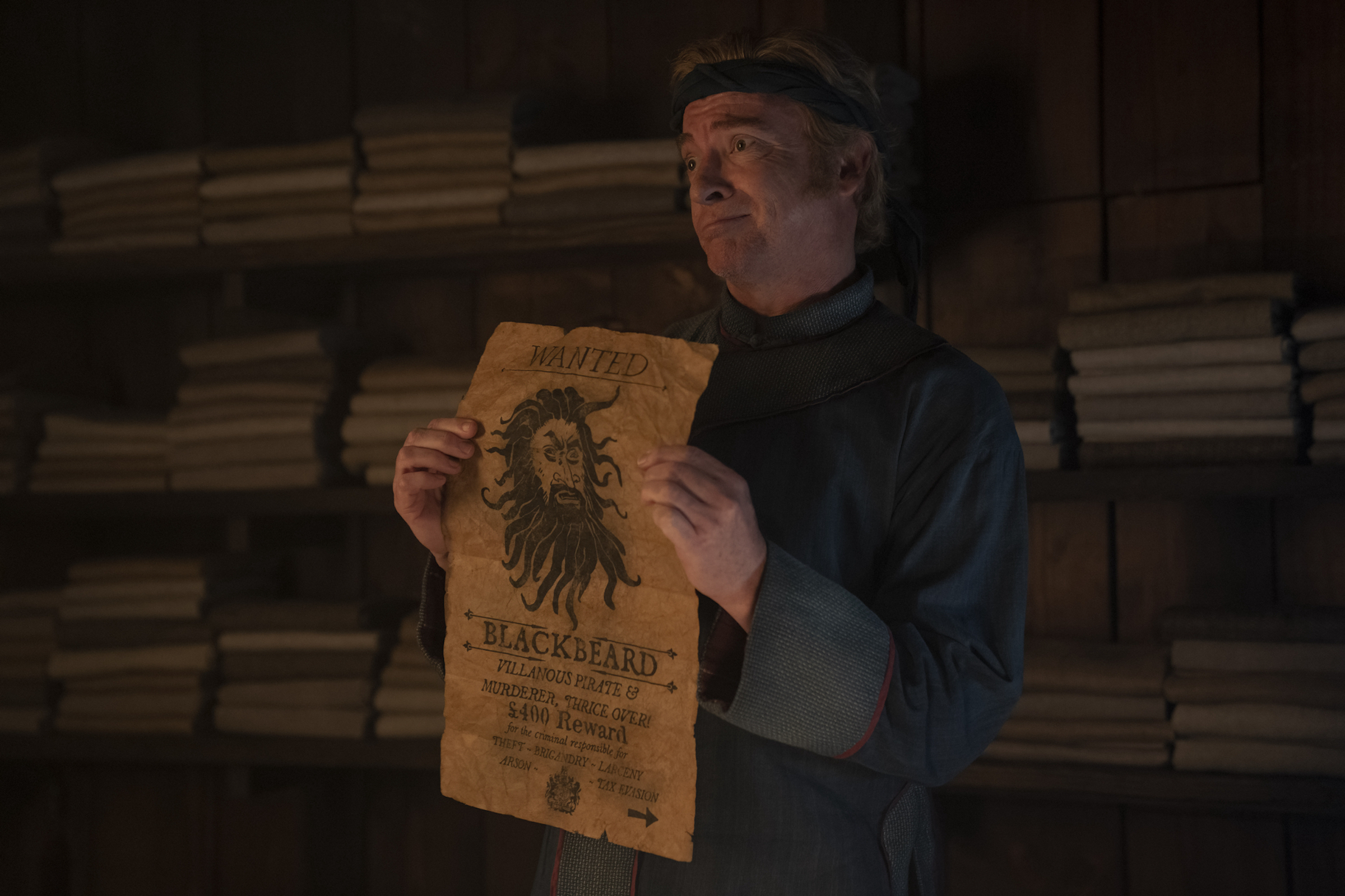 Stede Bonnet (Rhys Darby) pines after Blackbeard, pictured on a wanted poster, at the start of Season 2.