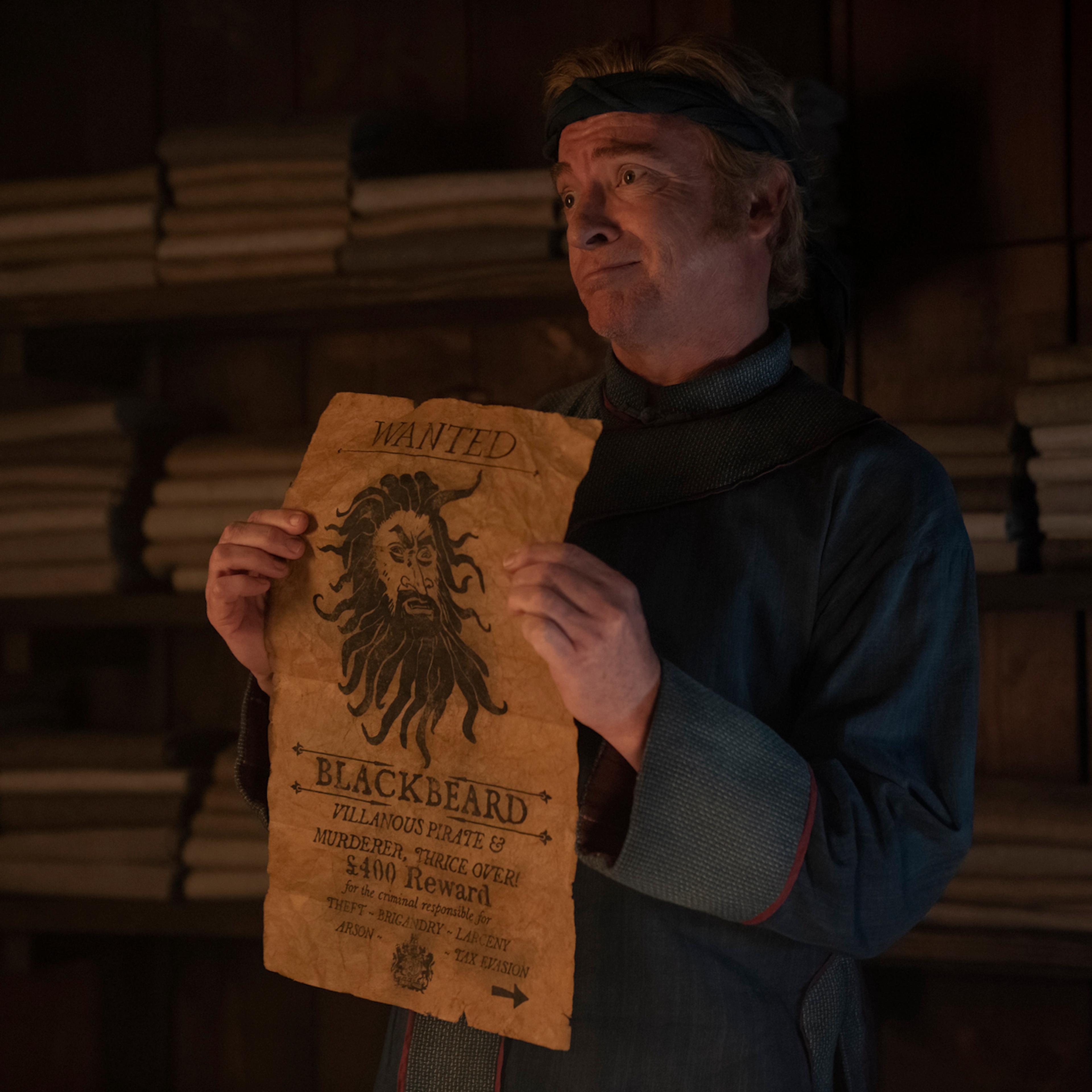 Stede Bonnet (Rhys Darby) pines after Blackbeard, pictured on a wanted poster, at the start of Season 2.