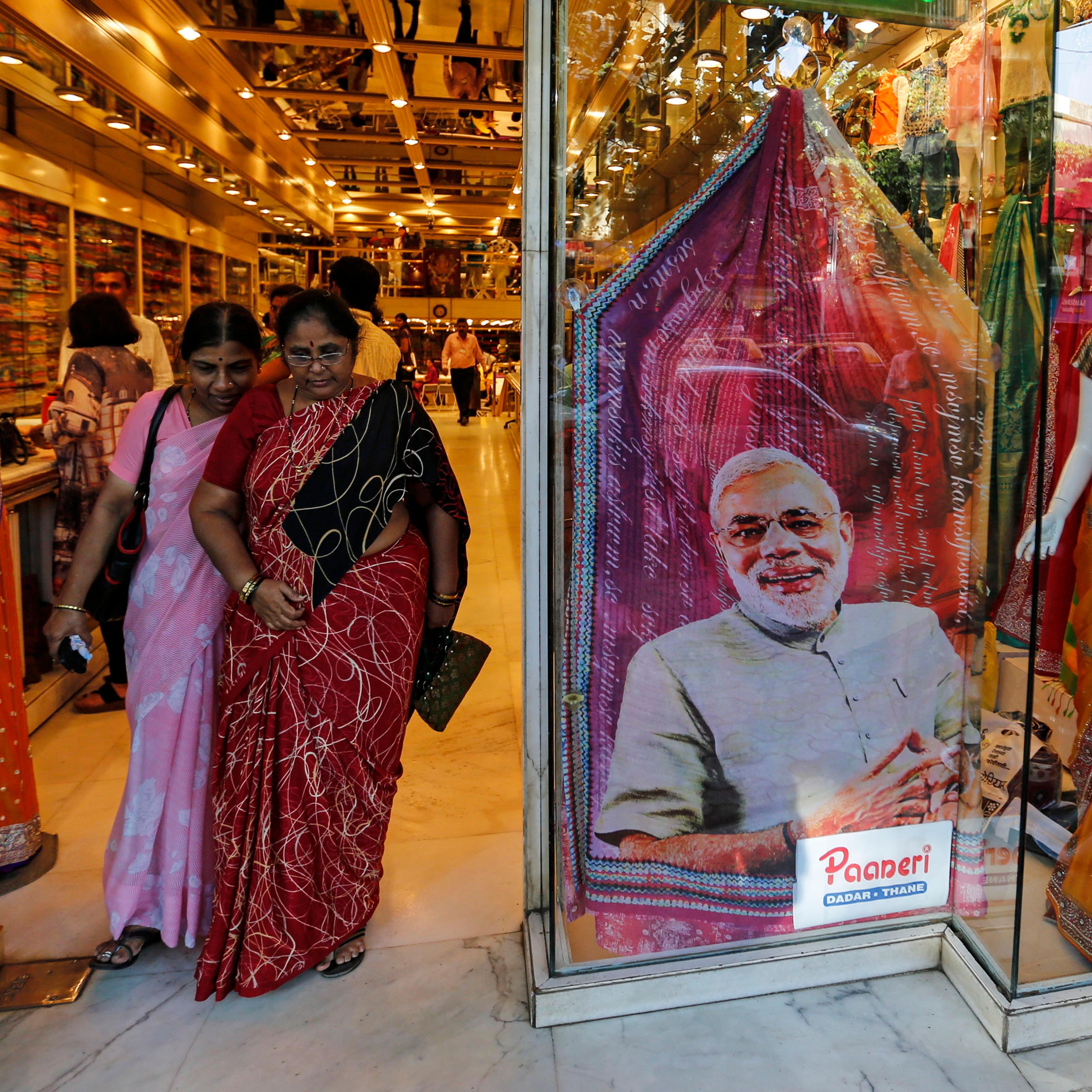 Customers walks past a sari, a traditional women's clothing, printed with a portrait of Hindu nationalist Narendra Modi, the prime ministerial candidate for India's main opposition Bharatiya Janata Party (BJP), at a showroom in Mumbai