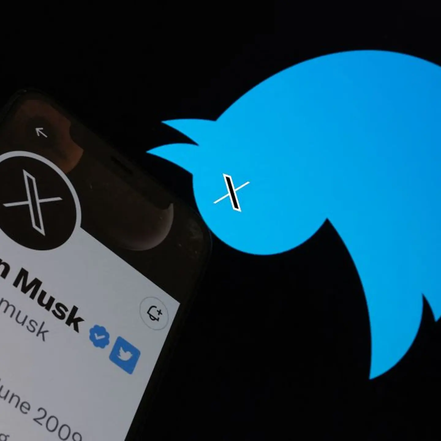 This illustration photo taken on July 24, 2023 shows the Twitter bird logo upside down in the background of Elon Musk's screen advertising an "X" as a replacement logo, in Los Angeles. Elon Musk killed off the Twitter logo on July 24, 2023, replacing the
