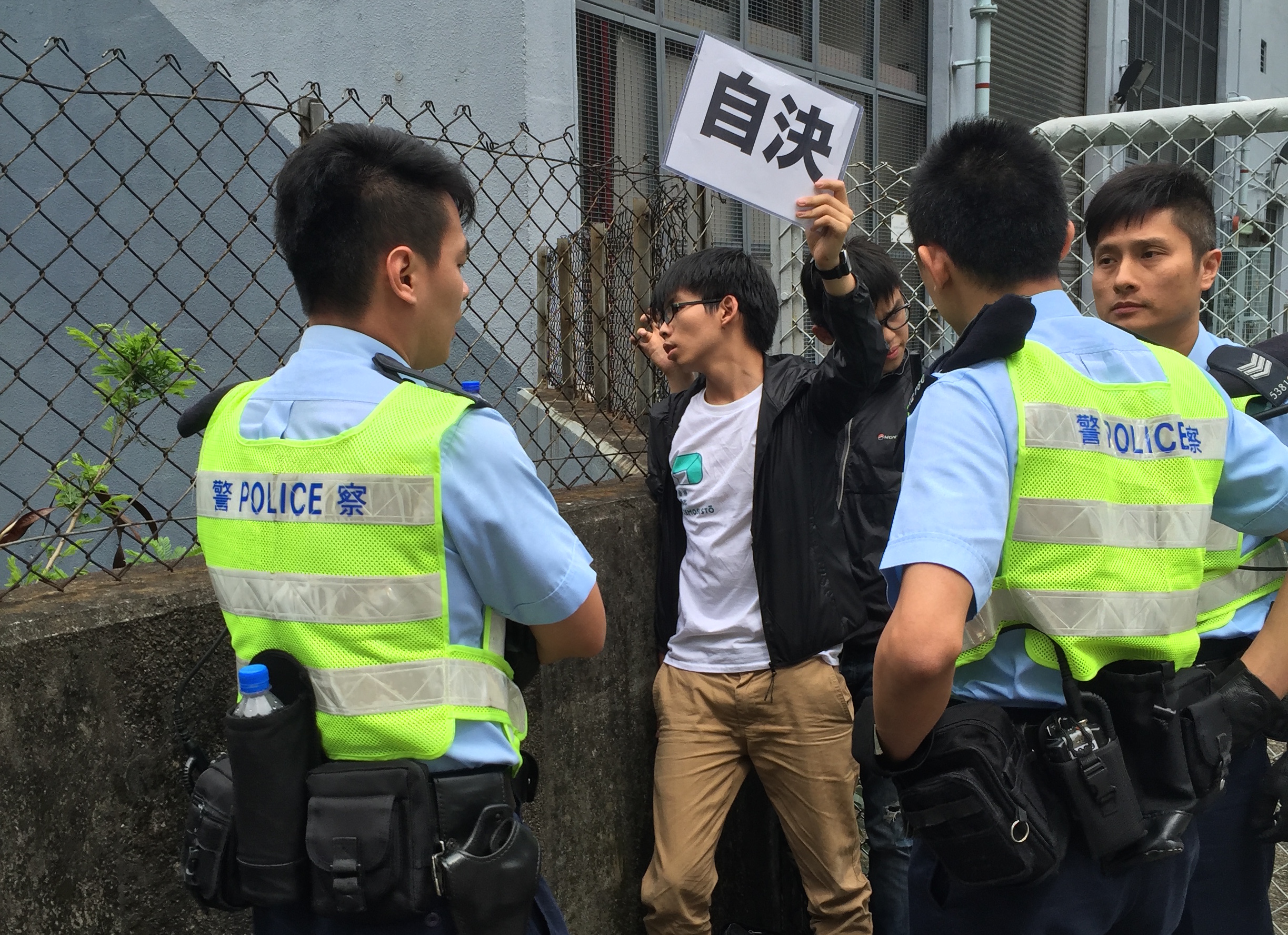 Student activist Joshua Wong holds up a pro-democracy placard that says "Self-Determination" after being detained by Hong Kong police on May 19, 2016 