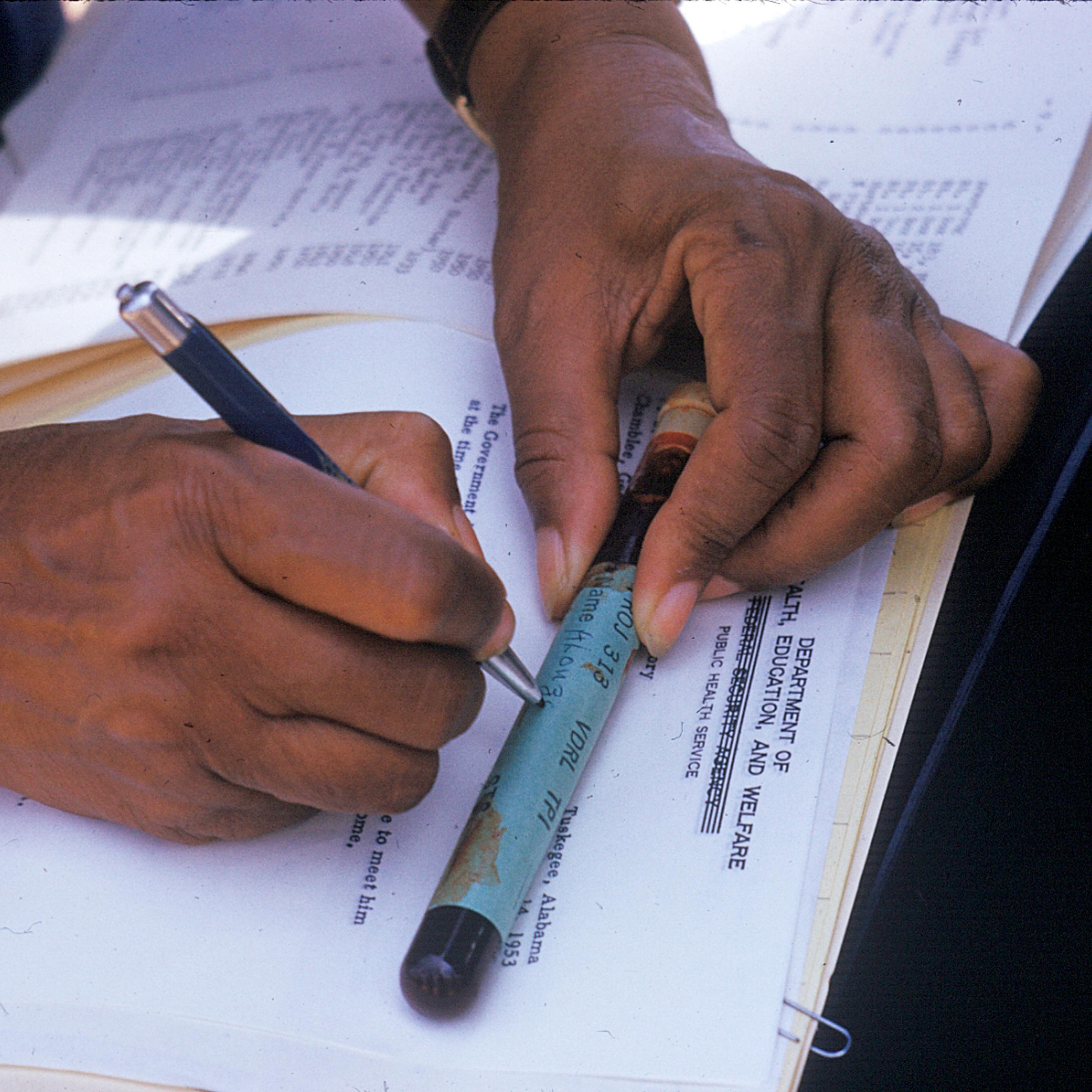 In this 1950's photo released by the National Archives, a nurse writes on a vial of blood taken from a participant in a syphilis study in Tuskegee, Ala.