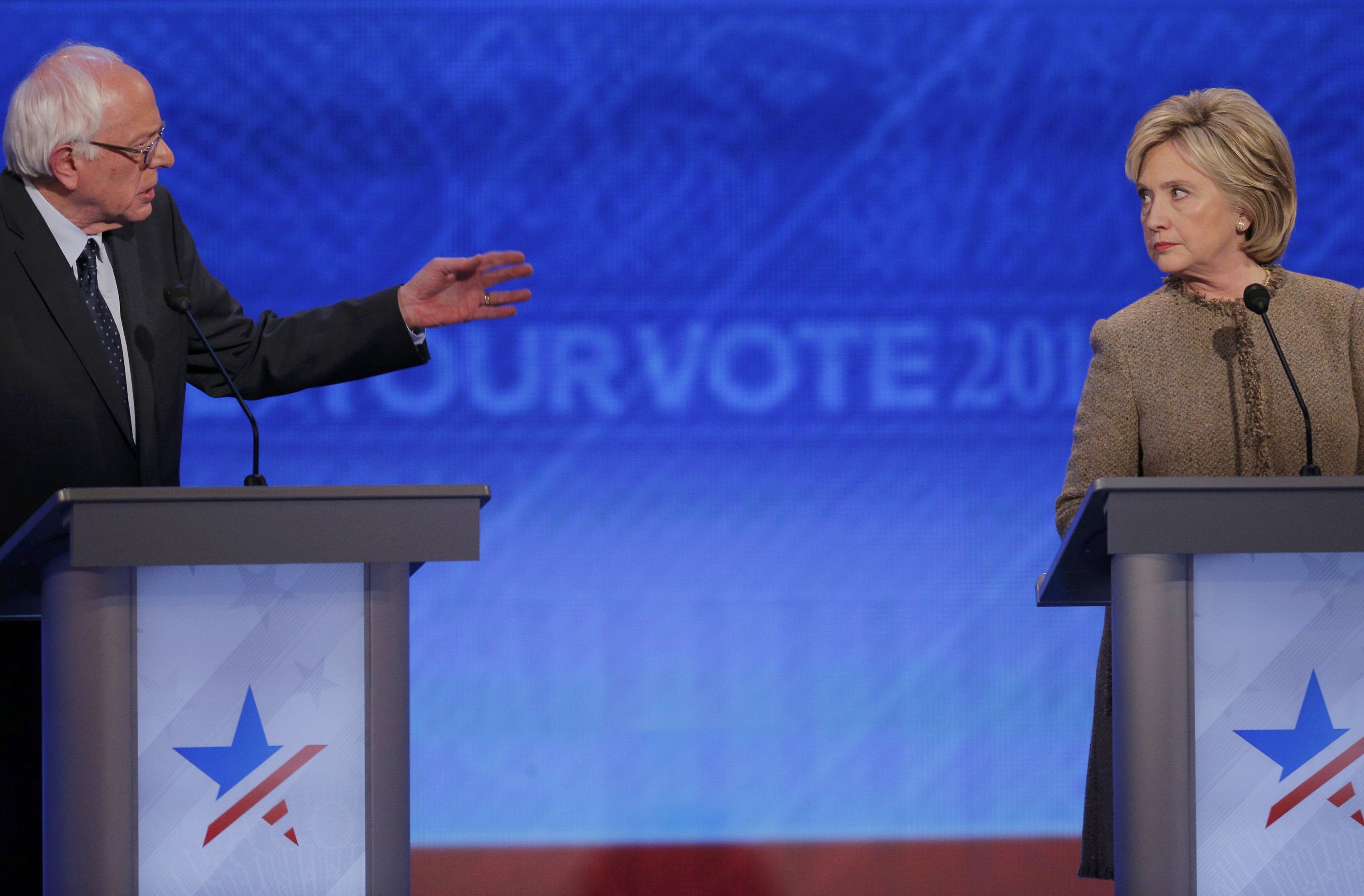 Democratic U.S. presidential candidate Clinton listens as Sanders answers a question at the Democratic presidential candidates debate at St. Anselm College in Manchester
