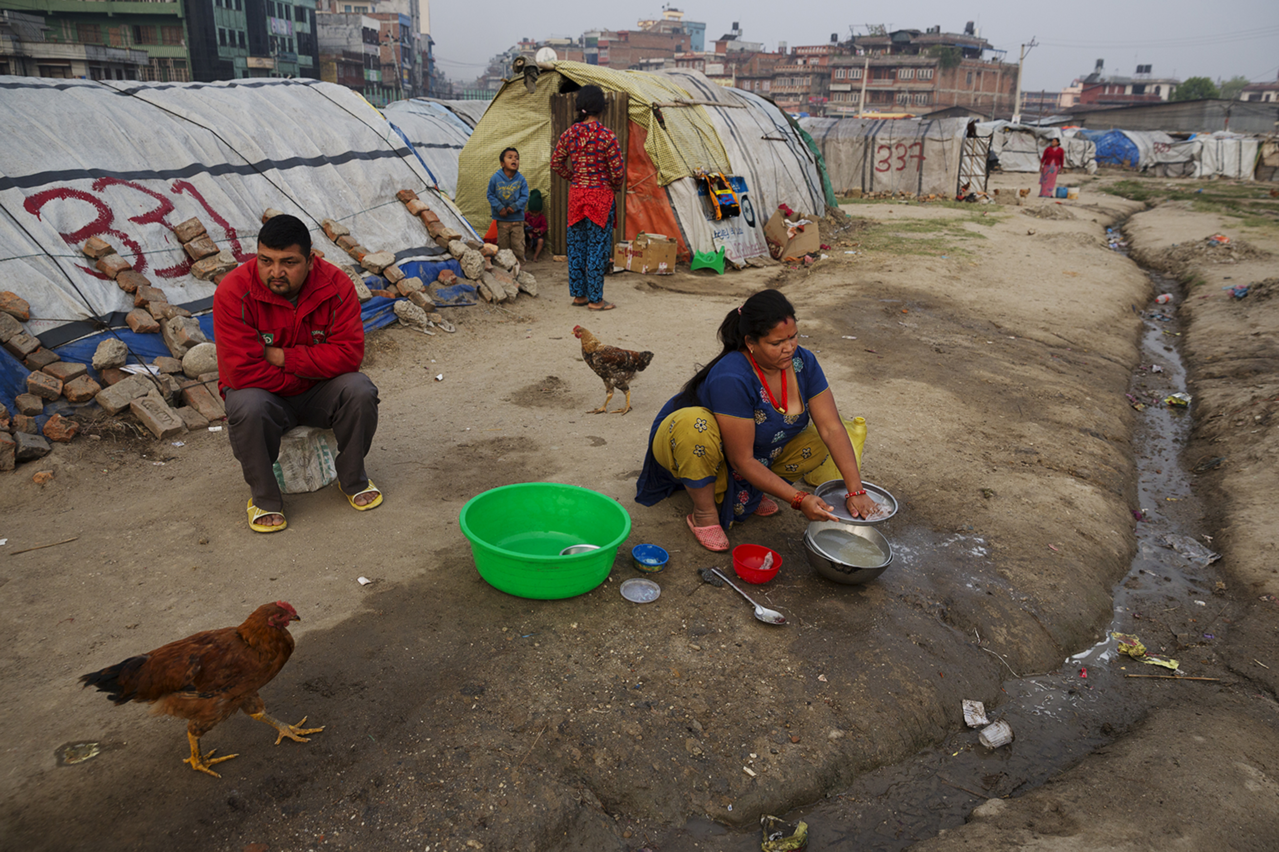 A family sits in an Informal tent encampment in central Kathmandu, Nepal. Approaching the first anniversary of the quakes of 2015, many people have been living in the squalid conditions of the camp for the past year. Some residents of the camp are from t