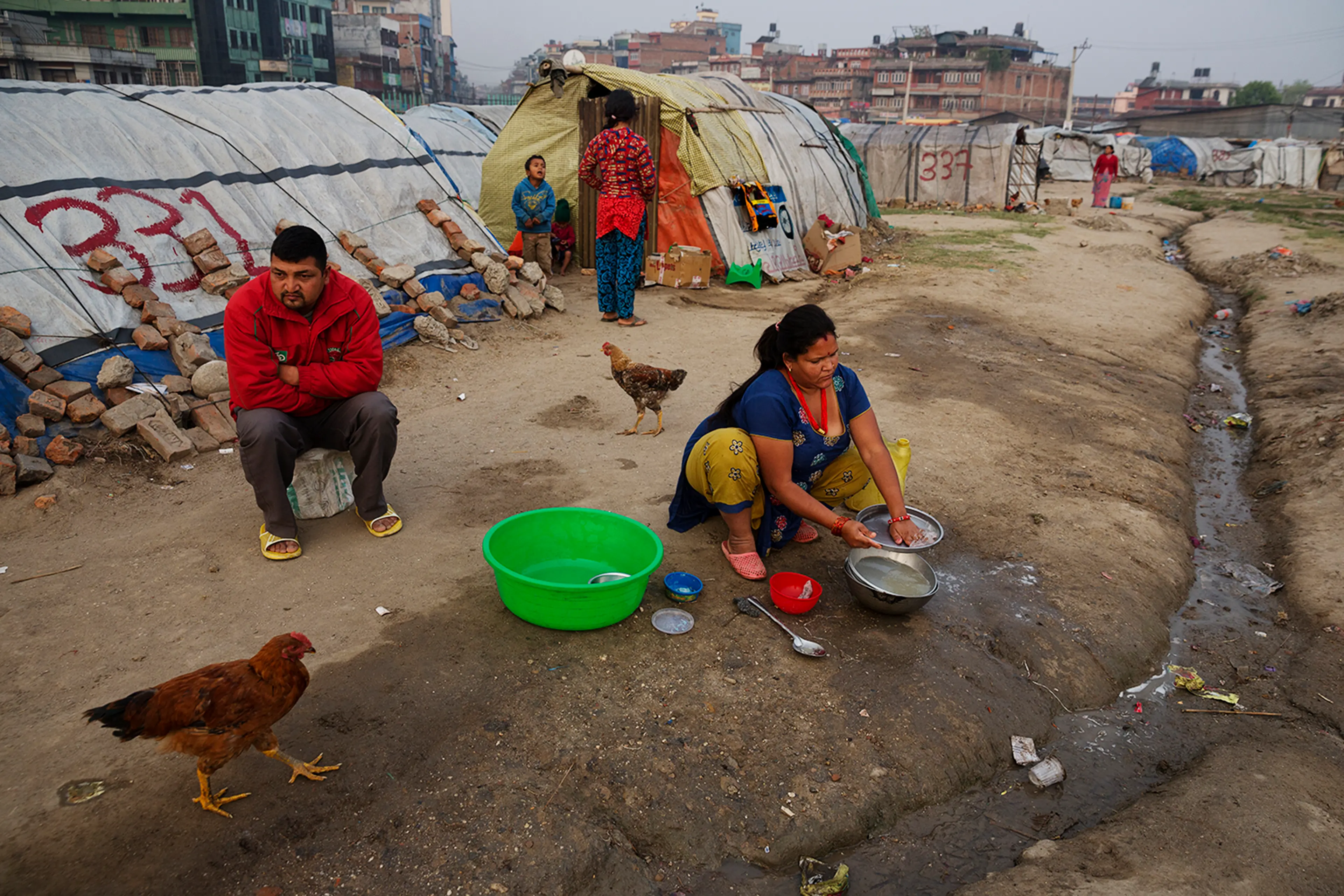 A family sits in an Informal tent encampment in central Kathmandu, Nepal. Approaching the first anniversary of the quakes of 2015, many people have been living in the squalid conditions of the camp for the past year. Some residents of the camp are from t