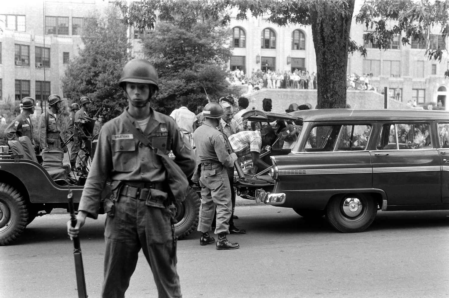 African-American students arrive at Little Rock Central High under heavy guard by troops from the 101st Airborne, 1957.