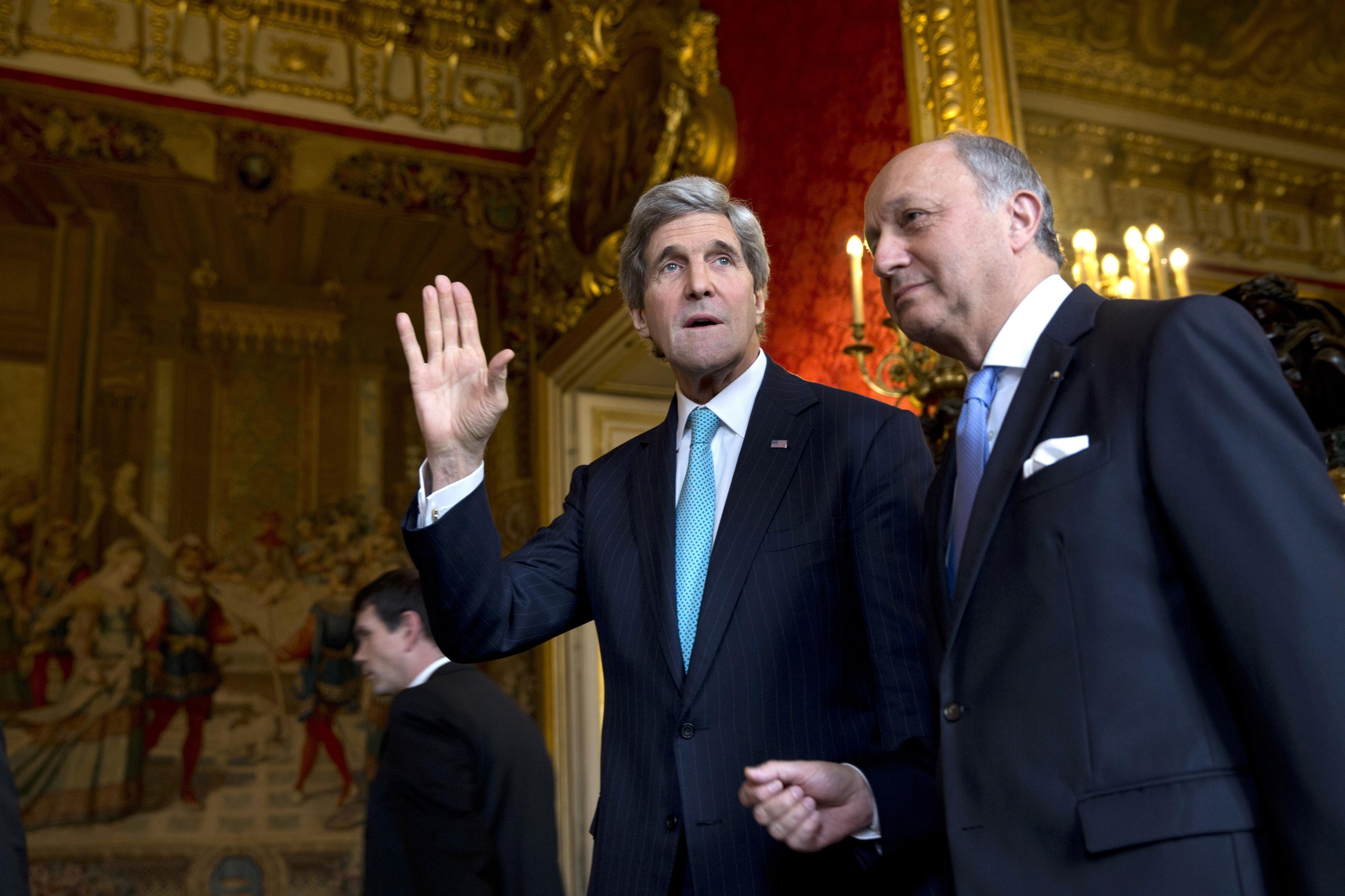 From left: U.S. Secretary of State John Kerry waves to the waiting media as he walks with French Foreign Minister Laurent Fabius for their meeting at the Quai d'Orsay in Paris, on March 30, 2014.
