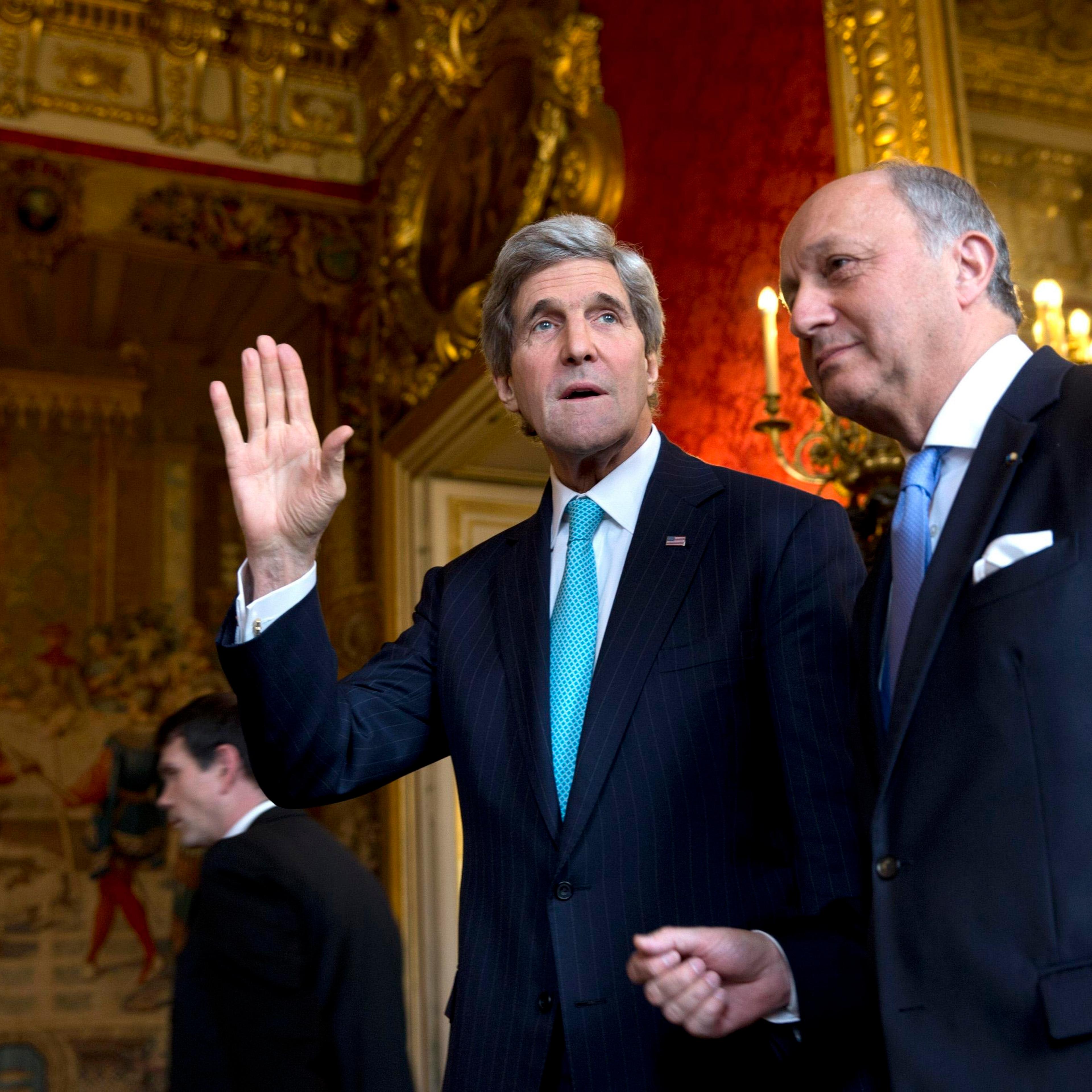 From left: U.S. Secretary of State John Kerry waves to the waiting media as he walks with French Foreign Minister Laurent Fabius for their meeting at the Quai d'Orsay in Paris, on March 30, 2014.