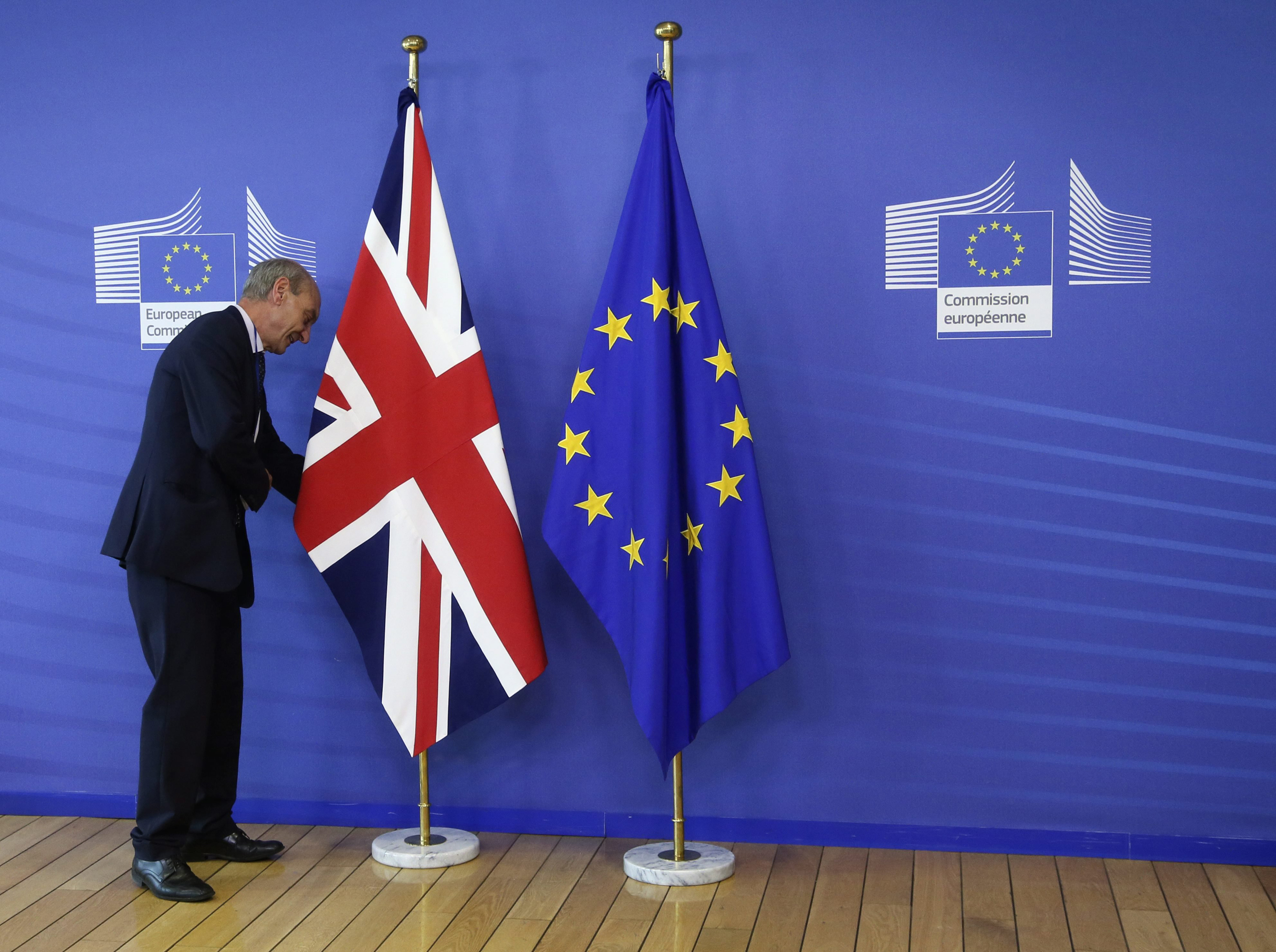 An employee of the European Commission arranges the flags prior to a meeting between Britain's Prime Minister David Cameron and European Commission President Jean- Claude Juncker in Brussels on June 28, 2016.