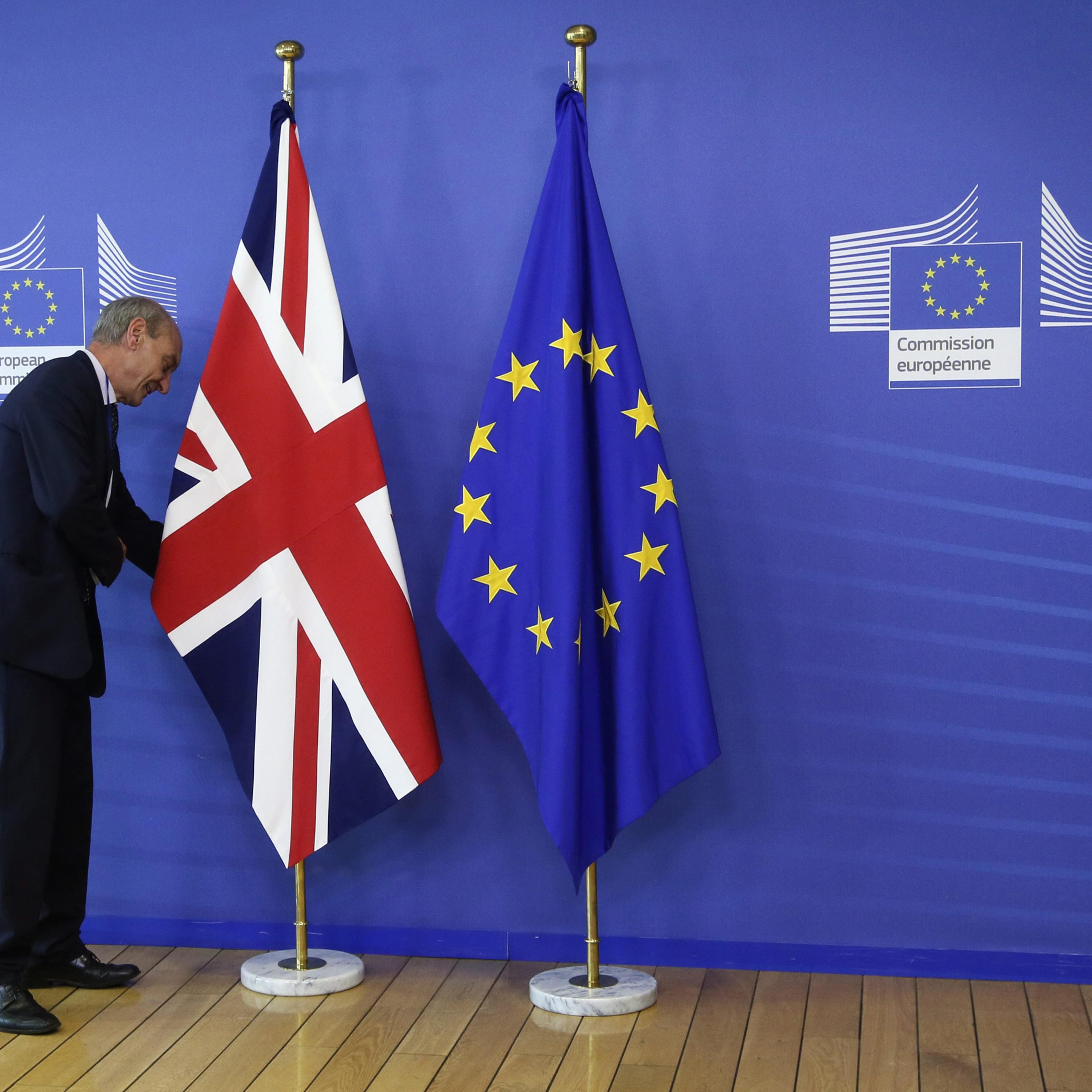 An employee of the European Commission arranges the flags prior to a meeting between Britain's Prime Minister David Cameron and European Commission President Jean- Claude Juncker in Brussels on June 28, 2016.