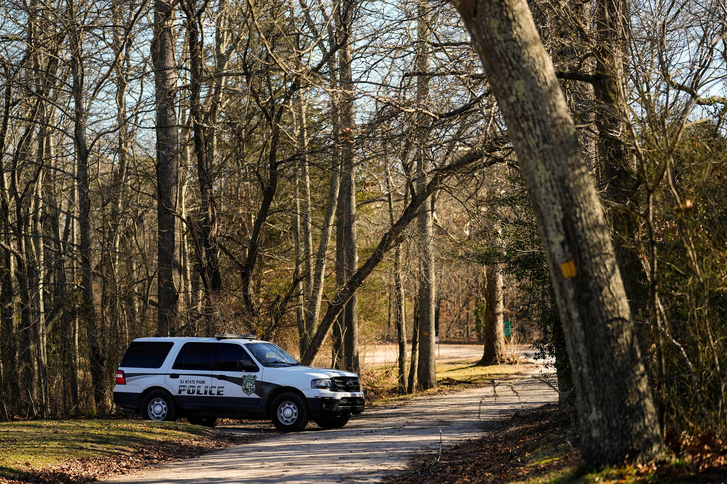 A police vehicle is parked on a road leading to the scene of a helicopter crash in Washington Township, N.J., Wednesday, Dec. 20, 2023. Investigators are examining the wreckage of a TV news helicopter that crashed in the New Jersey Pinelands, killing the pilot and a photographer on board. WPVI-TV of Philadelphia says a two members of its news team were in the helicopter when it went down about 8 p.m. Tuesday in Wharton State Forest.