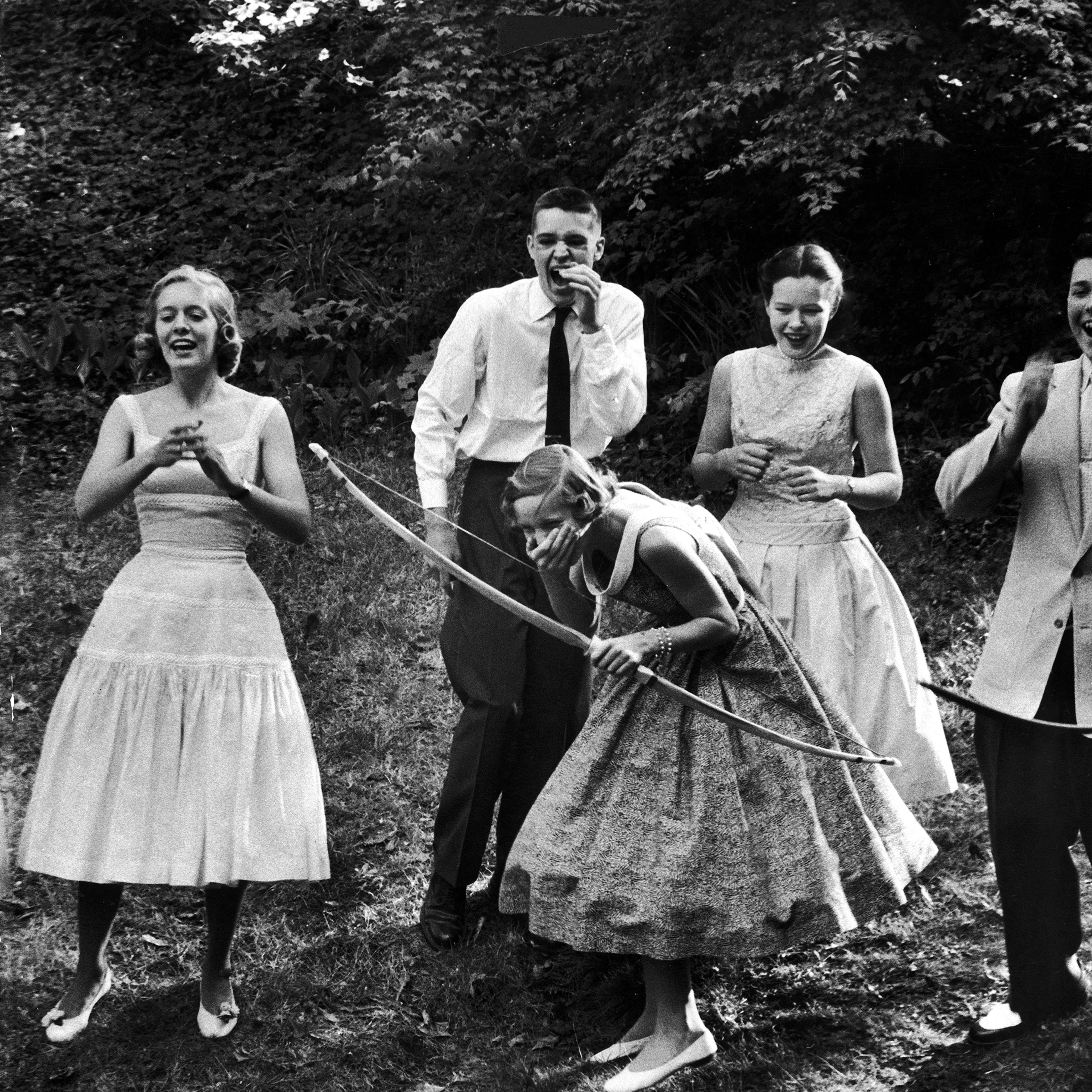 Archery providing entertainment for a group of friends at a teenage party, 1956.