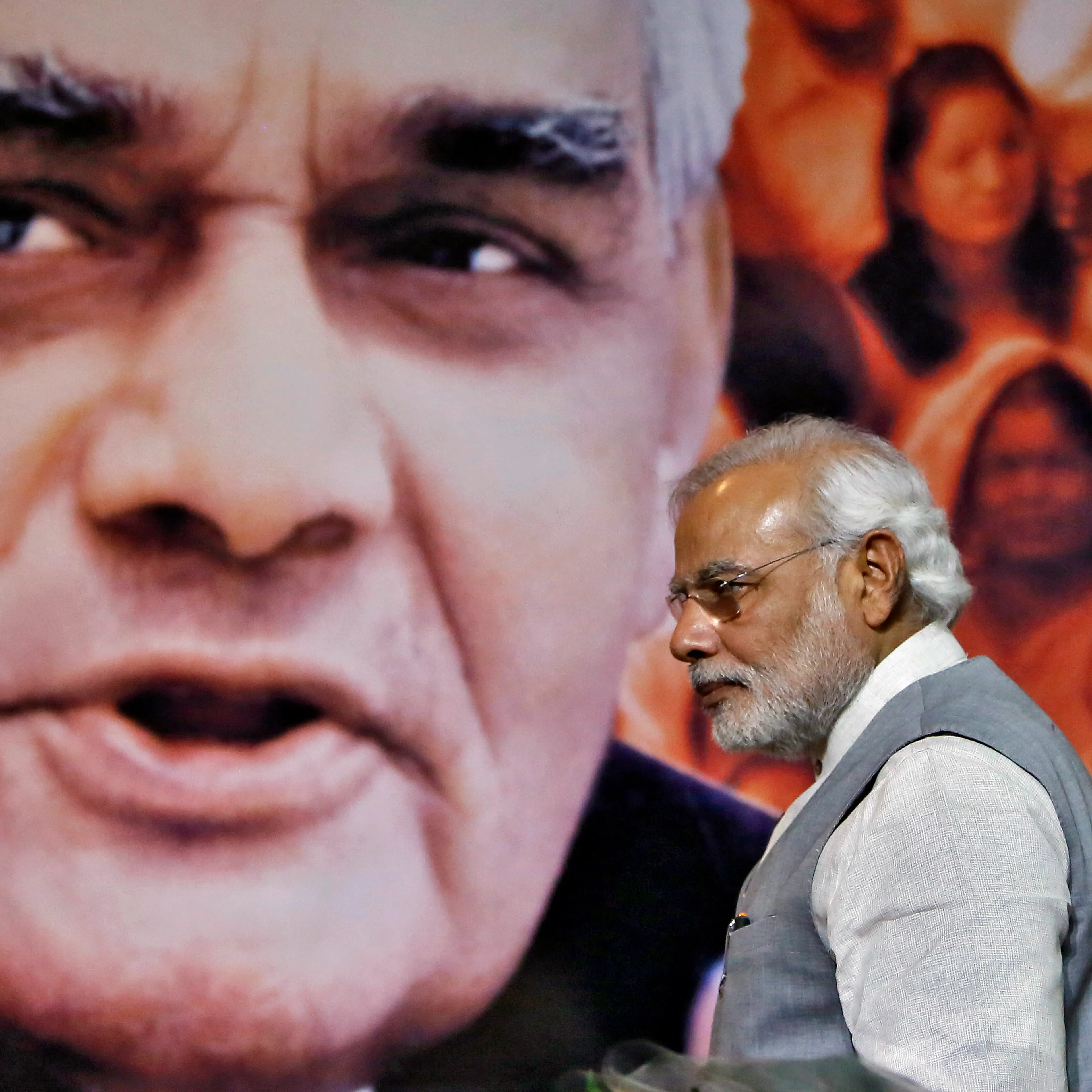 Indian PM Modi walks in front of a picture of former Indian PM Vajpayee after a news conference in New Delhi
