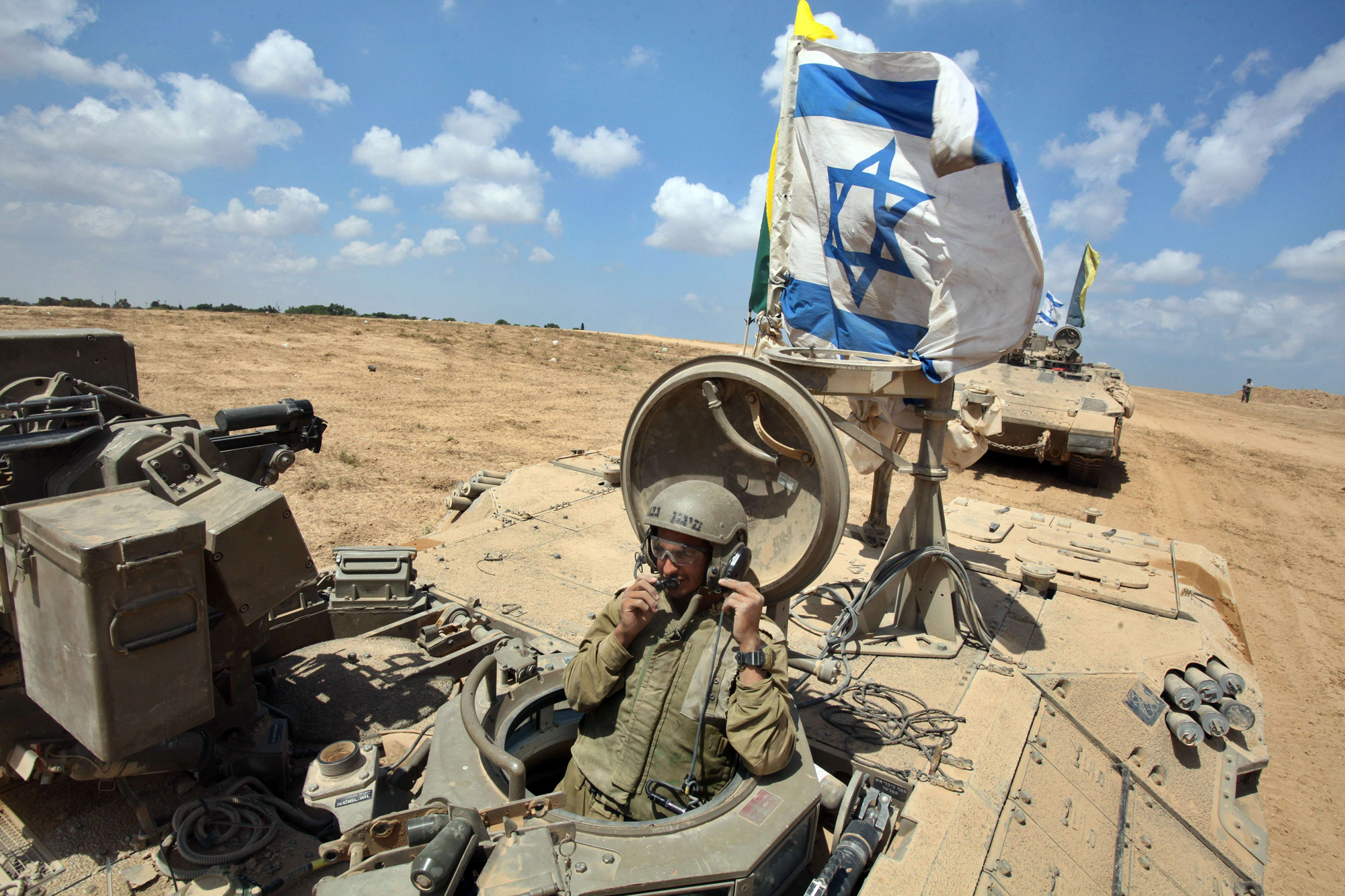 An Israeli soldier sits in an armored personnel carrier flying the Israeli flag as they return from the border between Israel and the Gaza Strip after pulling out of the Palestinian enclave on August 4, 2014 as Israel has begun withdrawing some ground tr