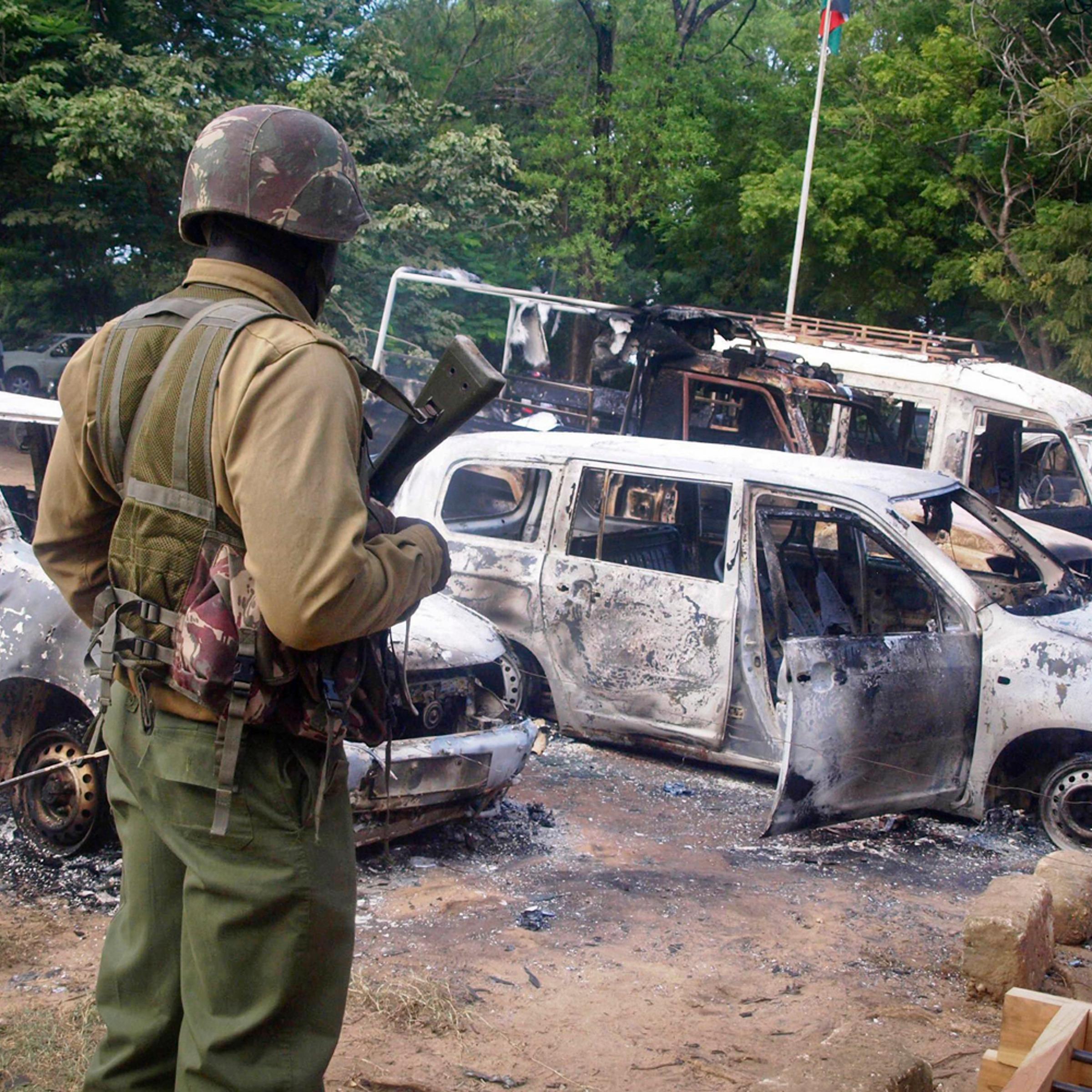 A member of the Kenyan security forces observes the remains of vehicles destroyed by militants, in the village of Kibaoni just outside the town of Mpeketoni, about 60 miles from the Somali border on the coast of Kenya, June 16, 2014.