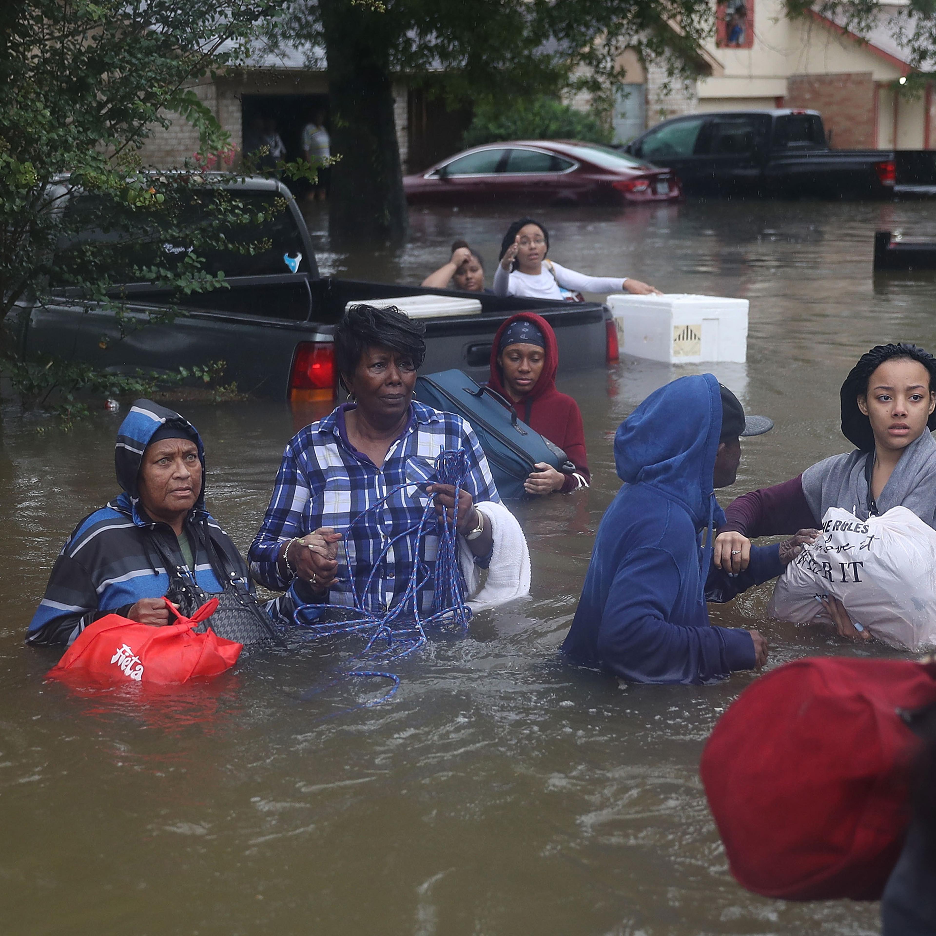 People walk down a flooded street as they evacuate their homes after the area was inundated with flooding from Hurricane Harvey on Aug. 28, 2017 in Houston.