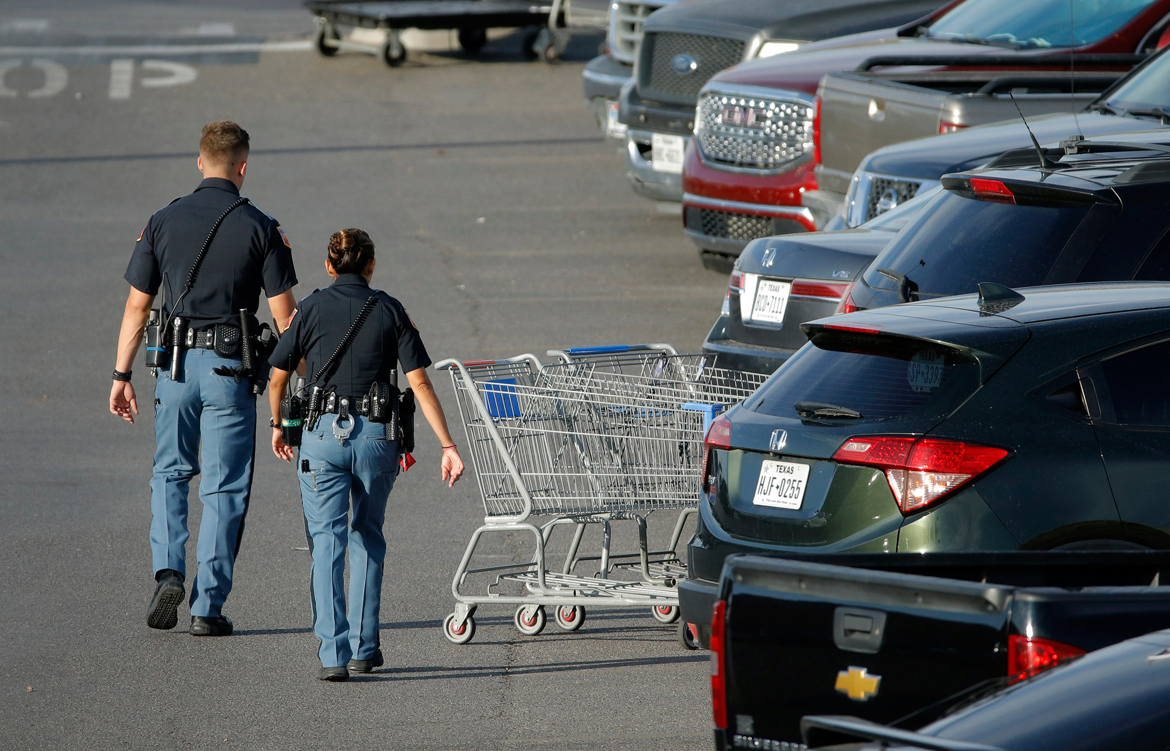 Police officers walk by shopping carts at the scene of the El Paso mass shooting, on Aug. 4