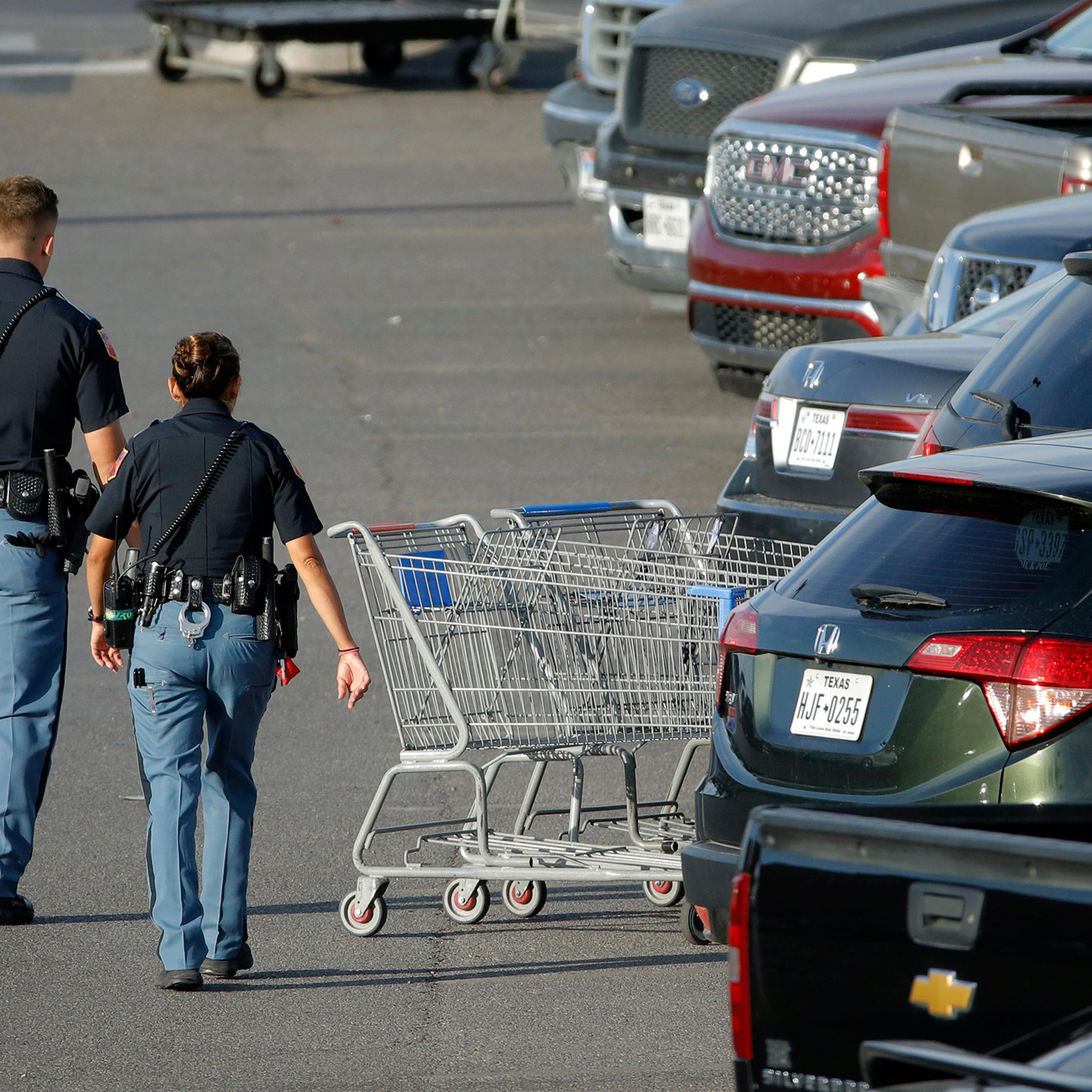 Police officers walk by shopping carts at the scene of the El Paso mass shooting, on Aug. 4