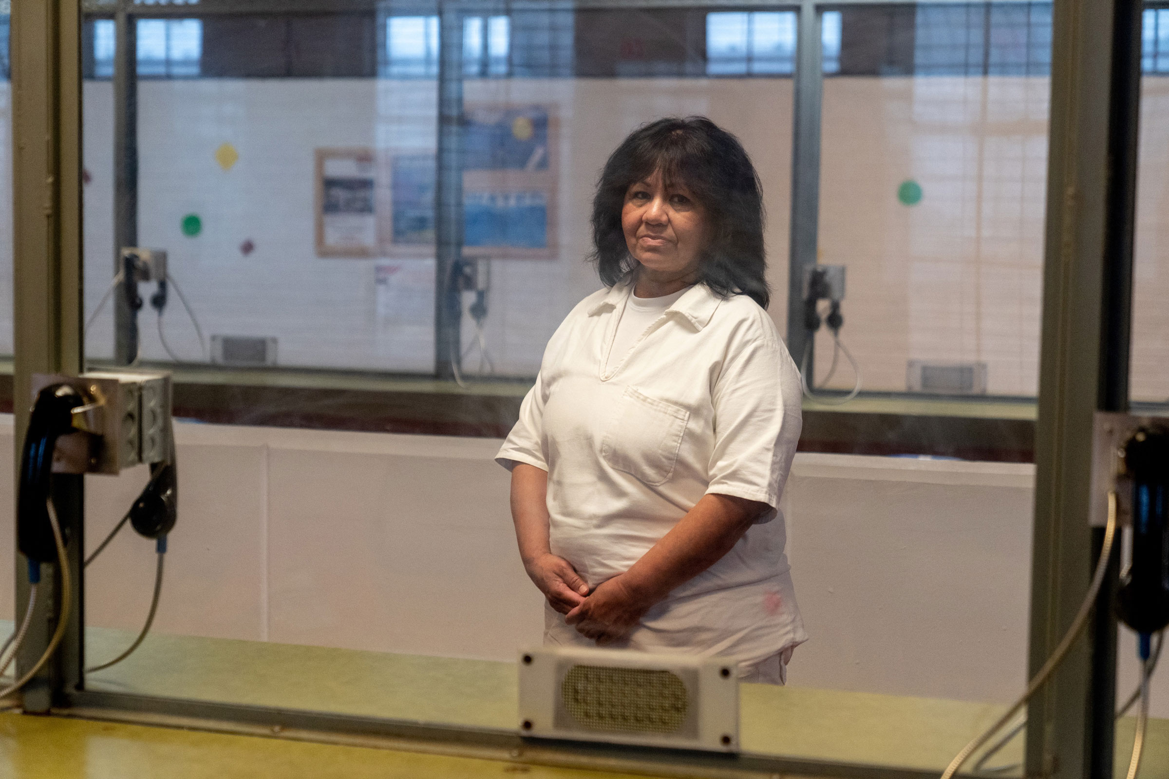 Melissa Lucio poses for a port​rait behind glass