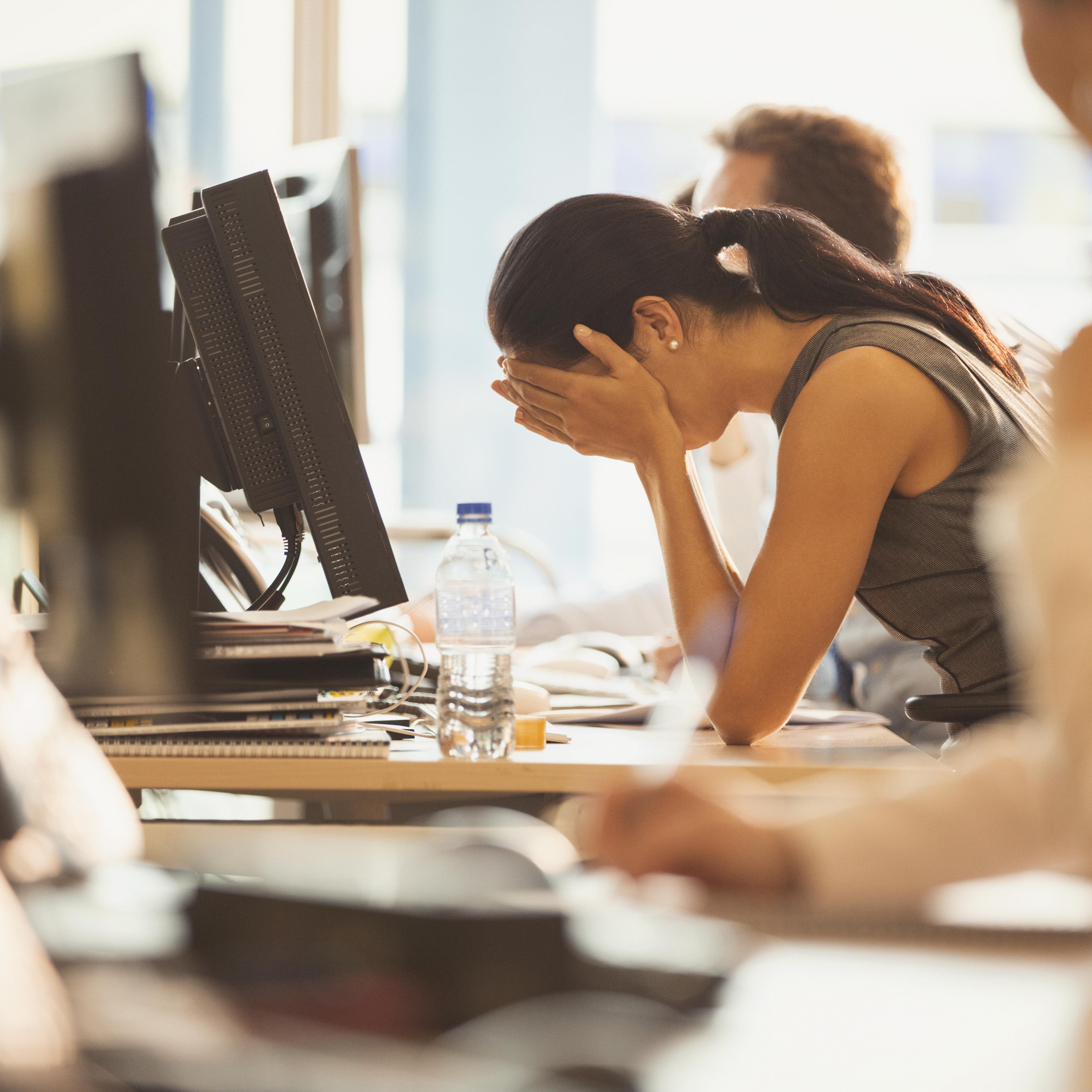 Stressed businesswoman with head in hands at office desk