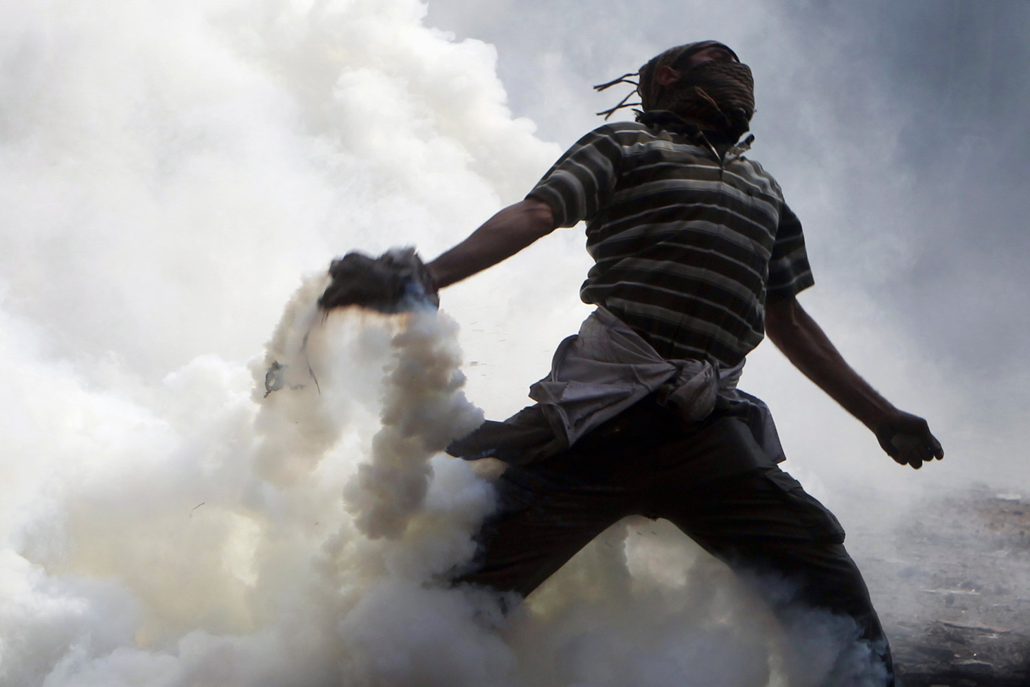 November 22, 2011. A protester tosses a tear gas canister, which was earlier thrown by riot police during clashes along a road which leads to the Interior Ministry, near Tahrir Square in Cairo. Egyptians frustrated with military rule battled police in the streets again on Nov. 22 as generals scrambled to cope with the cabinet's proffered resignation after bloodshed that has jolted plans for Egypt's first free election in decades. 
