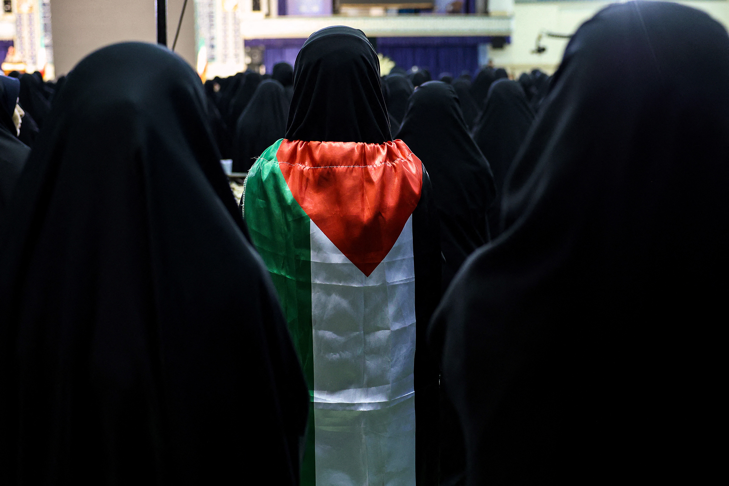 A woman wrapped in a Palestinian flag stands as Iranians attend a memorial ceremony for slain leader of the Palestinian Hamas group Ismail Haniyeh at the Mosallah mosque in Tehran, on Aug. 9 2024. 