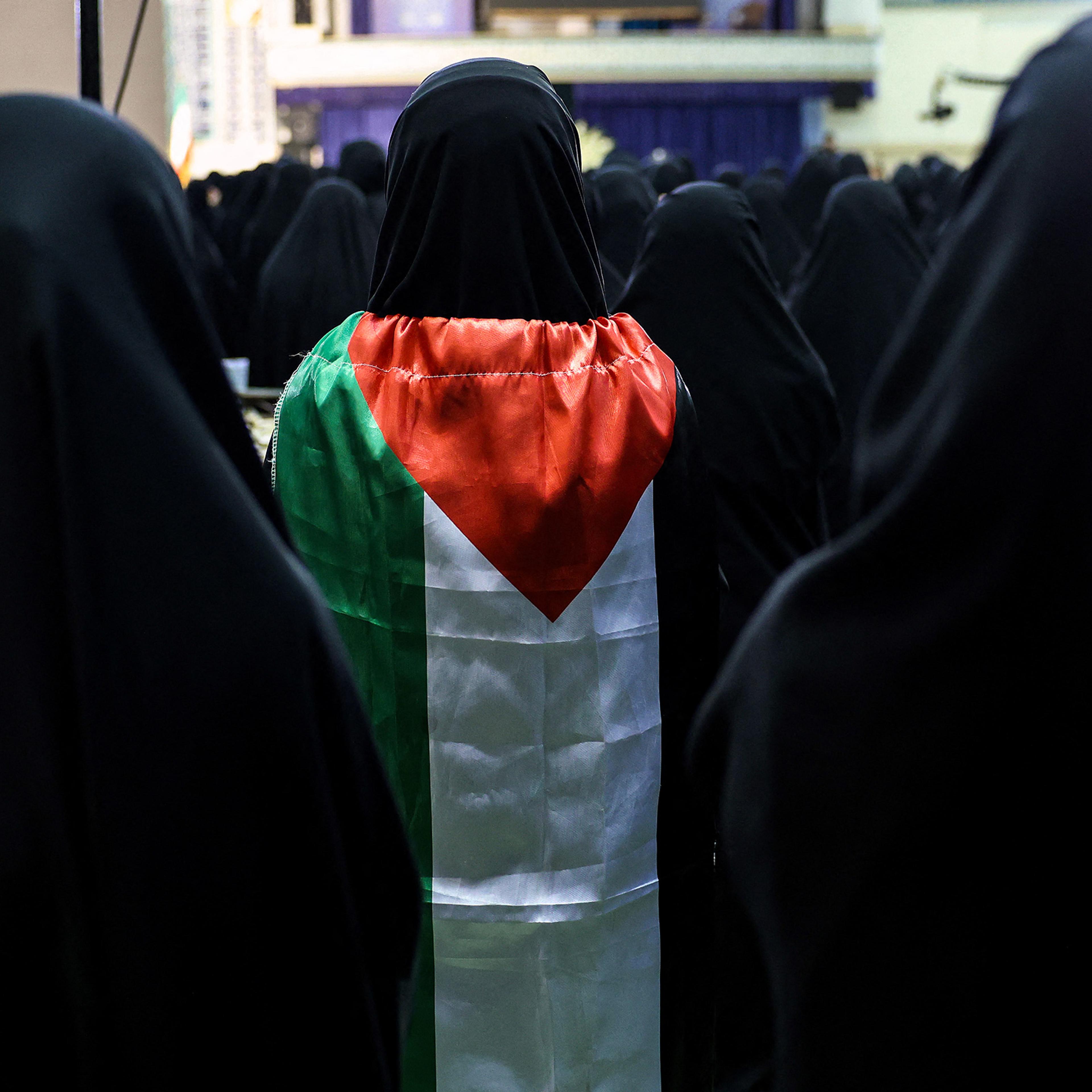 A woman wrapped in a Palestinian flag stands as Iranians attend a memorial ceremony for slain leader of the Palestinian Hamas group Ismail Haniyeh at the Mosallah mosque in Tehran, on Aug. 9 2024.