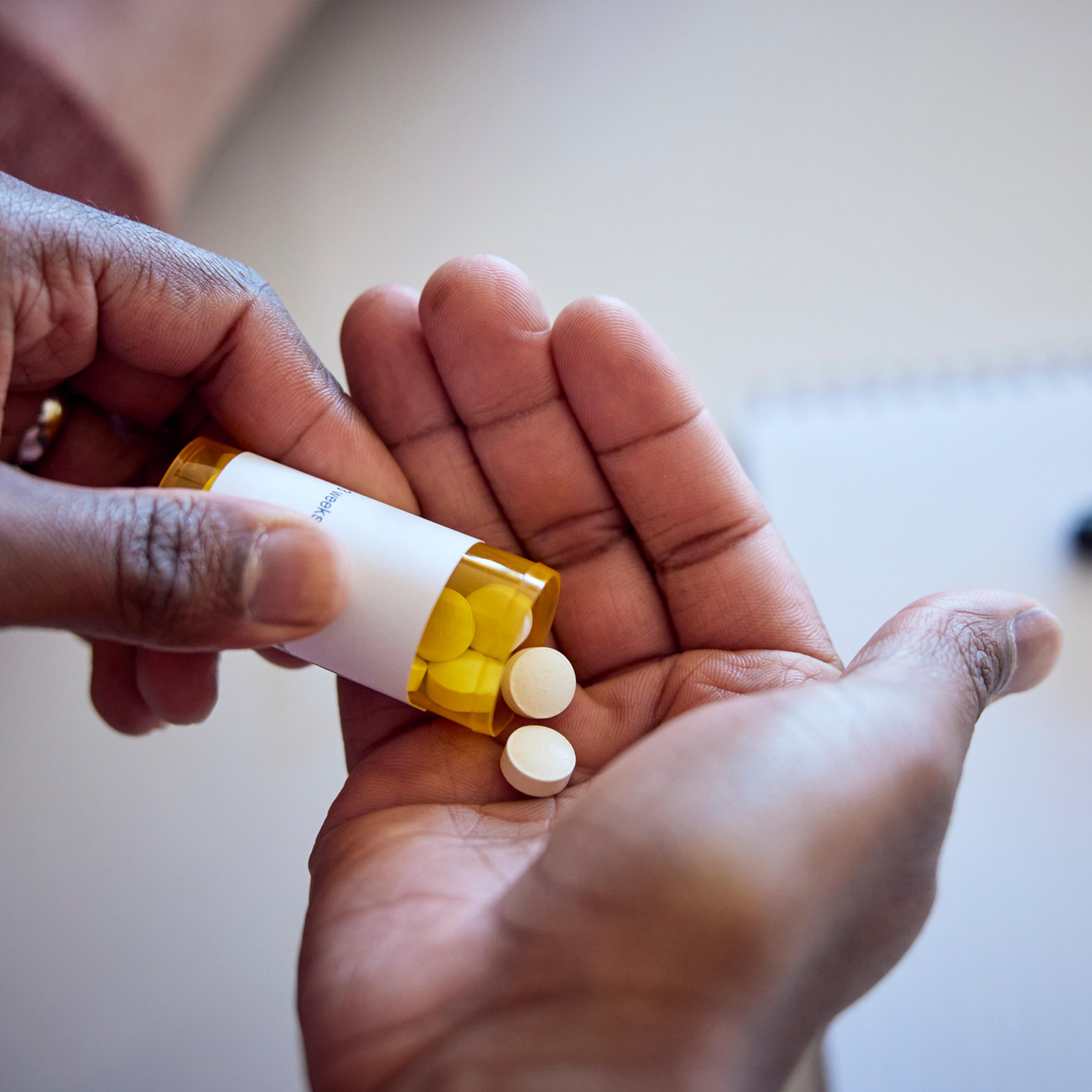 Man pouring pills into hand