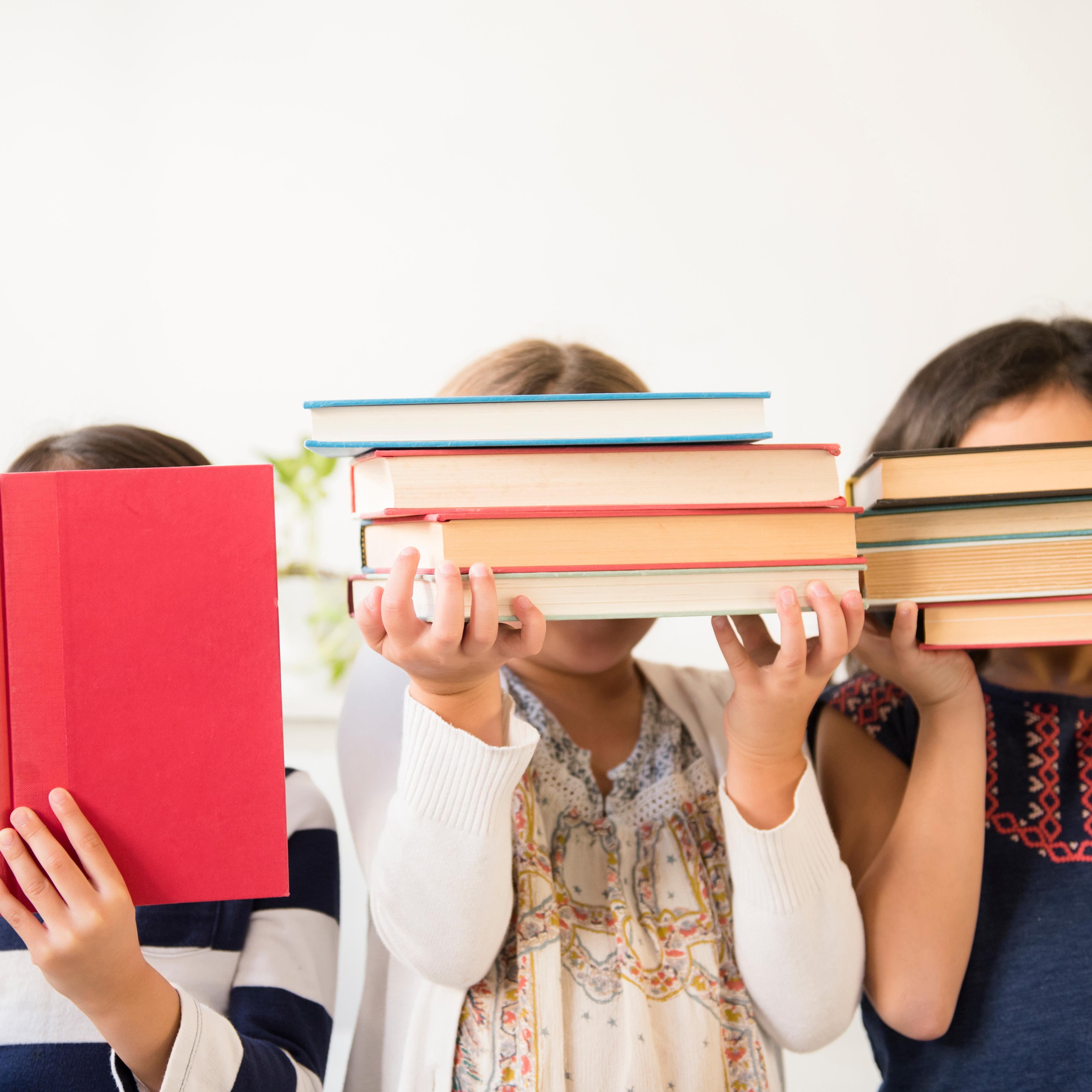 Girls holding books in front of faces