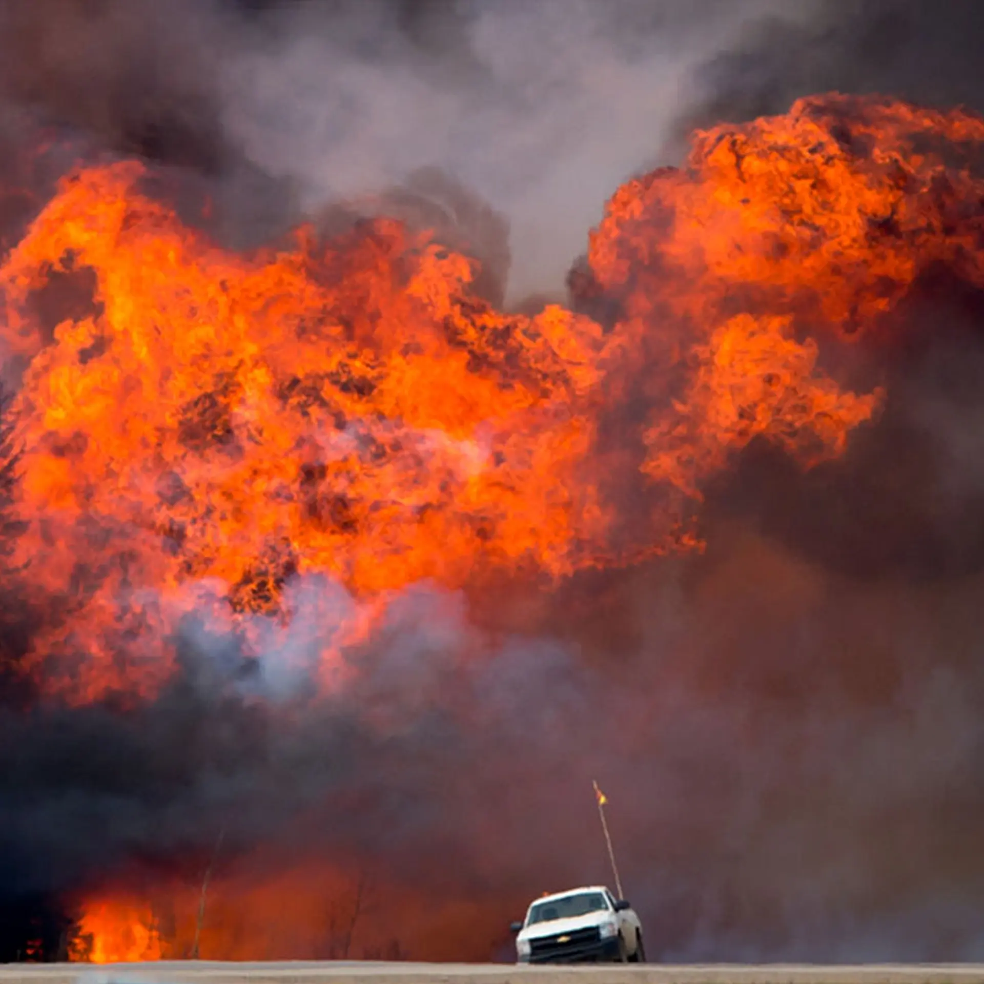 A wildfire burns behind an abandoned truck on Alberta Highway 63 near Fort McMurray, Alberta, Canada, on May 7, 2016.