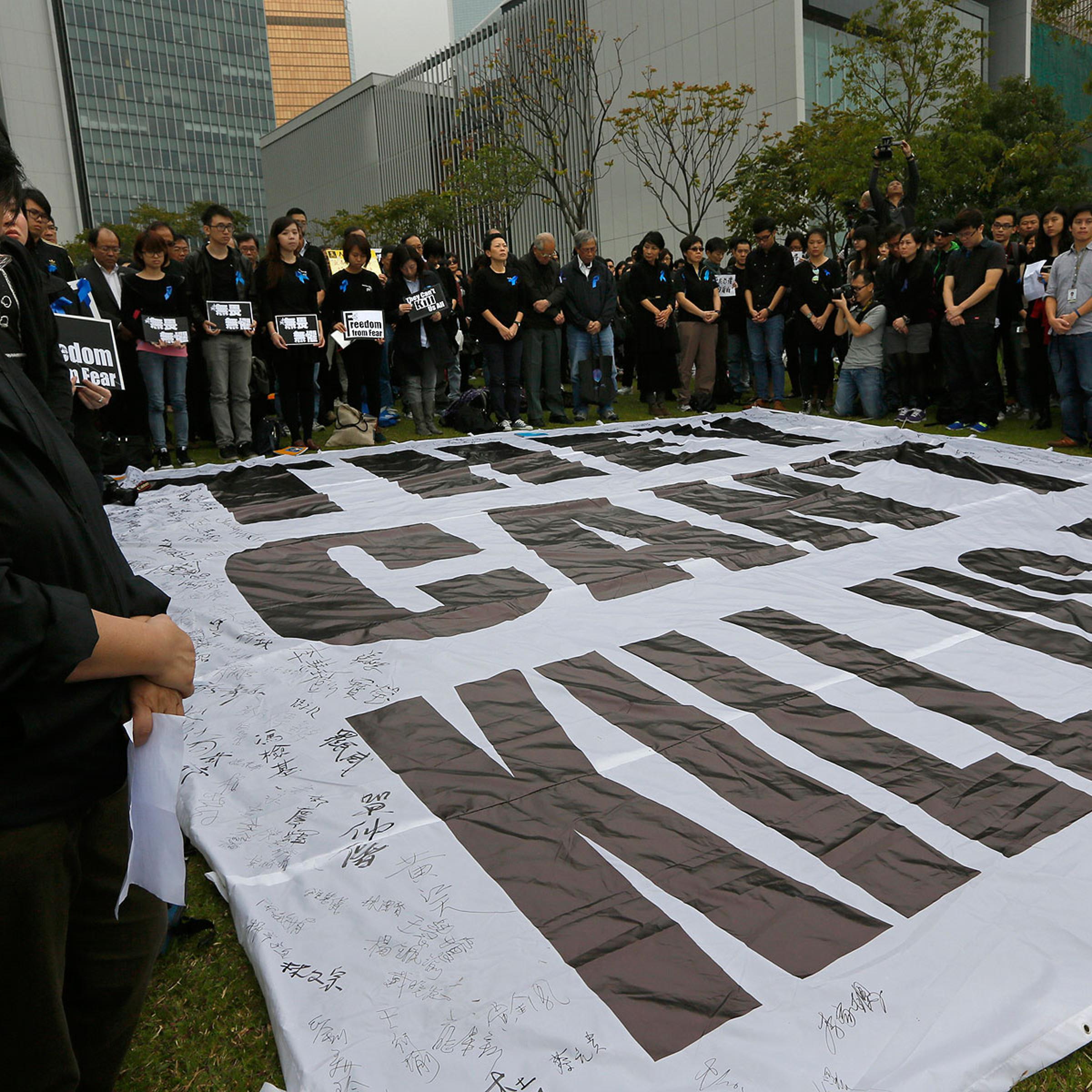 Journalists and their supporters stand in a five minutes silent around a huge banner reads " They can't kill us all " during a rally outside the government headquarter in Hong Kong, March 2, 2014