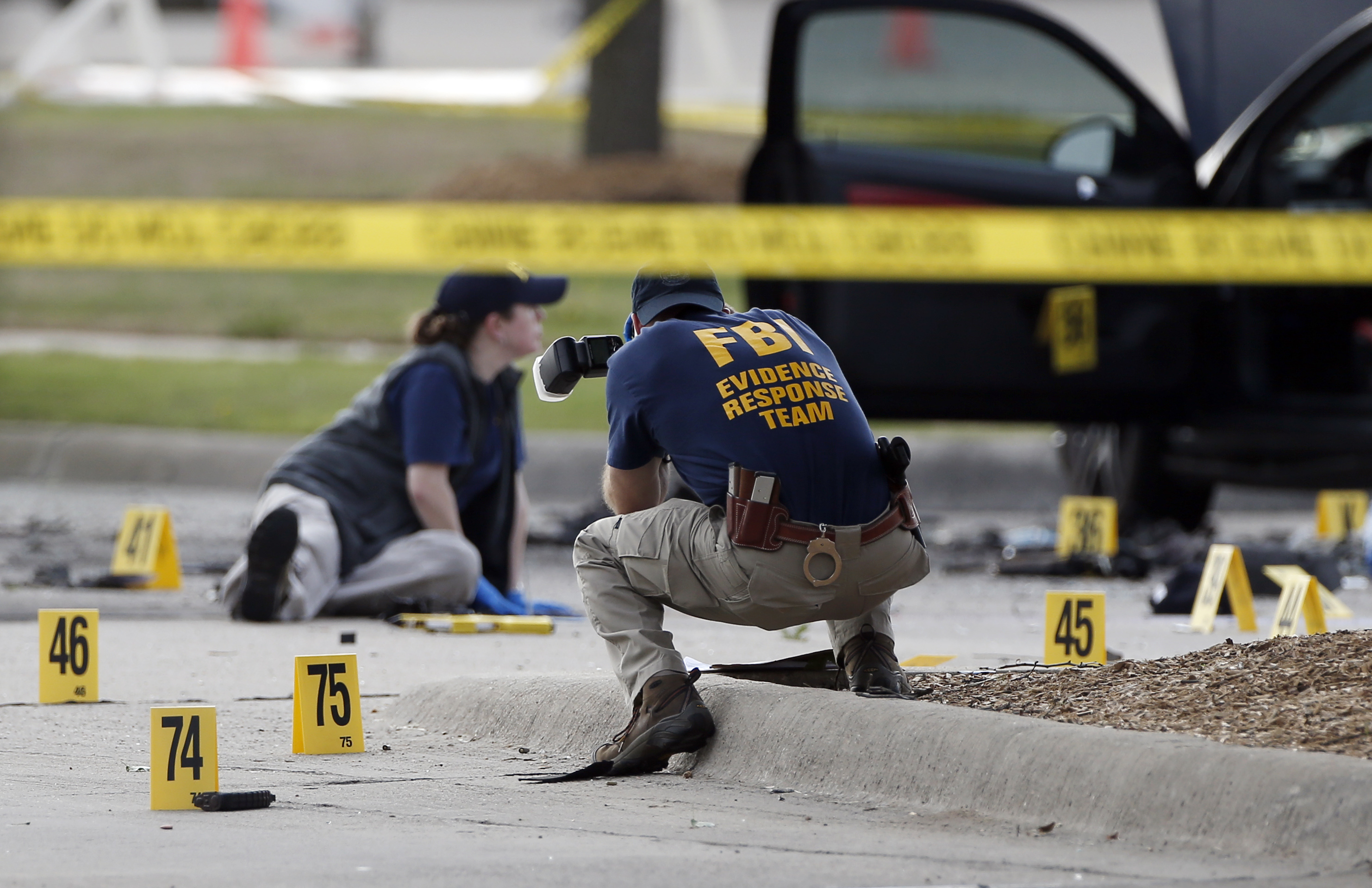 FBI crime scene investigators document the area around two deceased gunmen and their vehicle outside the Curtis Culwell Center in Garland, Texas, Monday, May 4, 2015. Police shot and killed the men after they opened fire on a security officer outside the