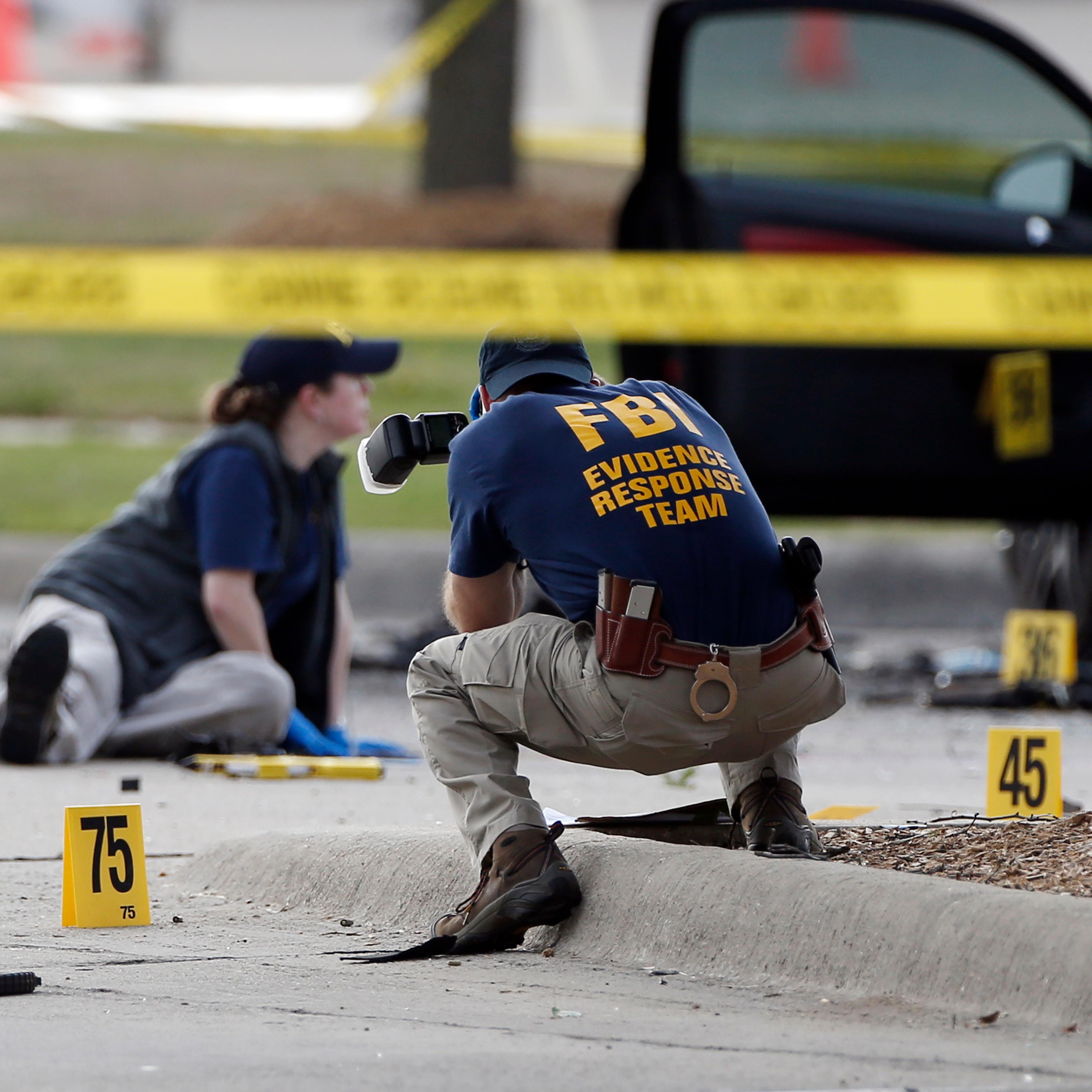 FBI crime scene investigators document the area around two deceased gunmen and their vehicle outside the Curtis Culwell Center in Garland, Texas, Monday, May 4, 2015. Police shot and killed the men after they opened fire on a security officer outside the