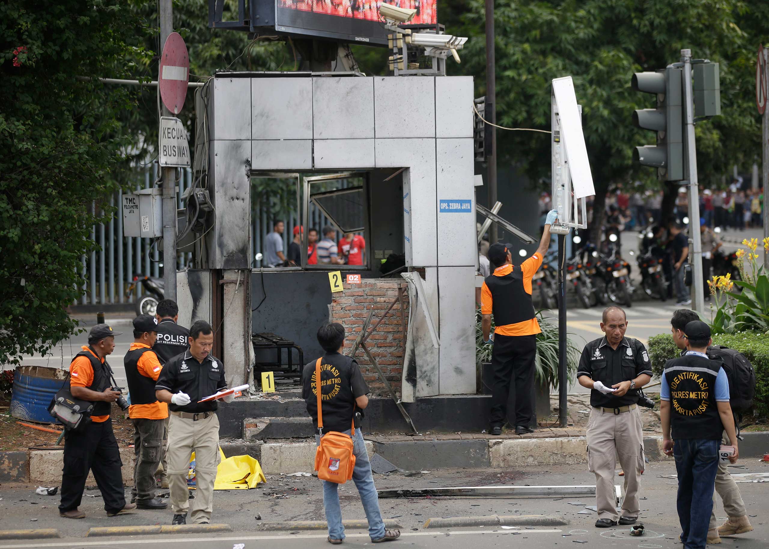 Officers examine a police post where an explosion went off in Jakarta, Indonesia, Jan. 14, 2016. Attackers set off explosions in a bustling shopping area in Indonesia's capital and waged gun battles with police, leaving bodies in the streets as office wo