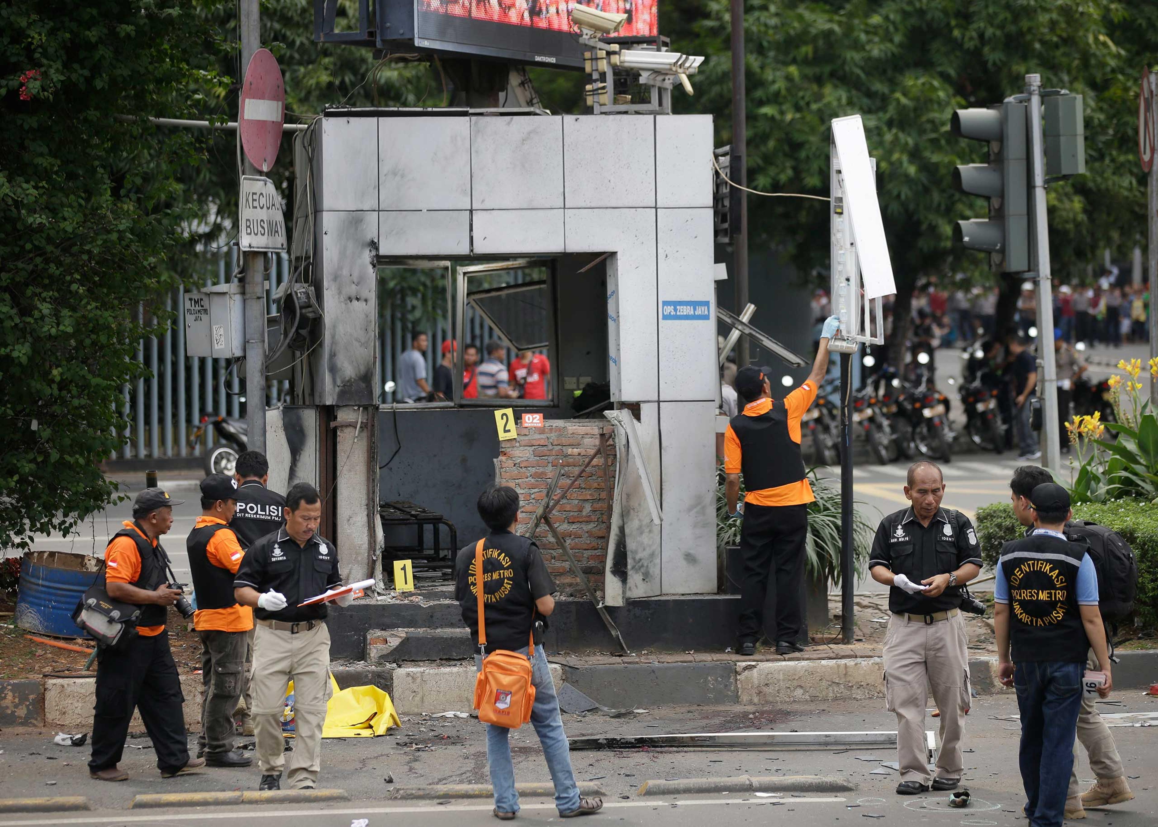 Officers examine a police post where an explosion went off in Jakarta, Indonesia, Jan. 14, 2016. Attackers set off explosions in a bustling shopping area in Indonesia's capital and waged gun battles with police, leaving bodies in the streets as office wo