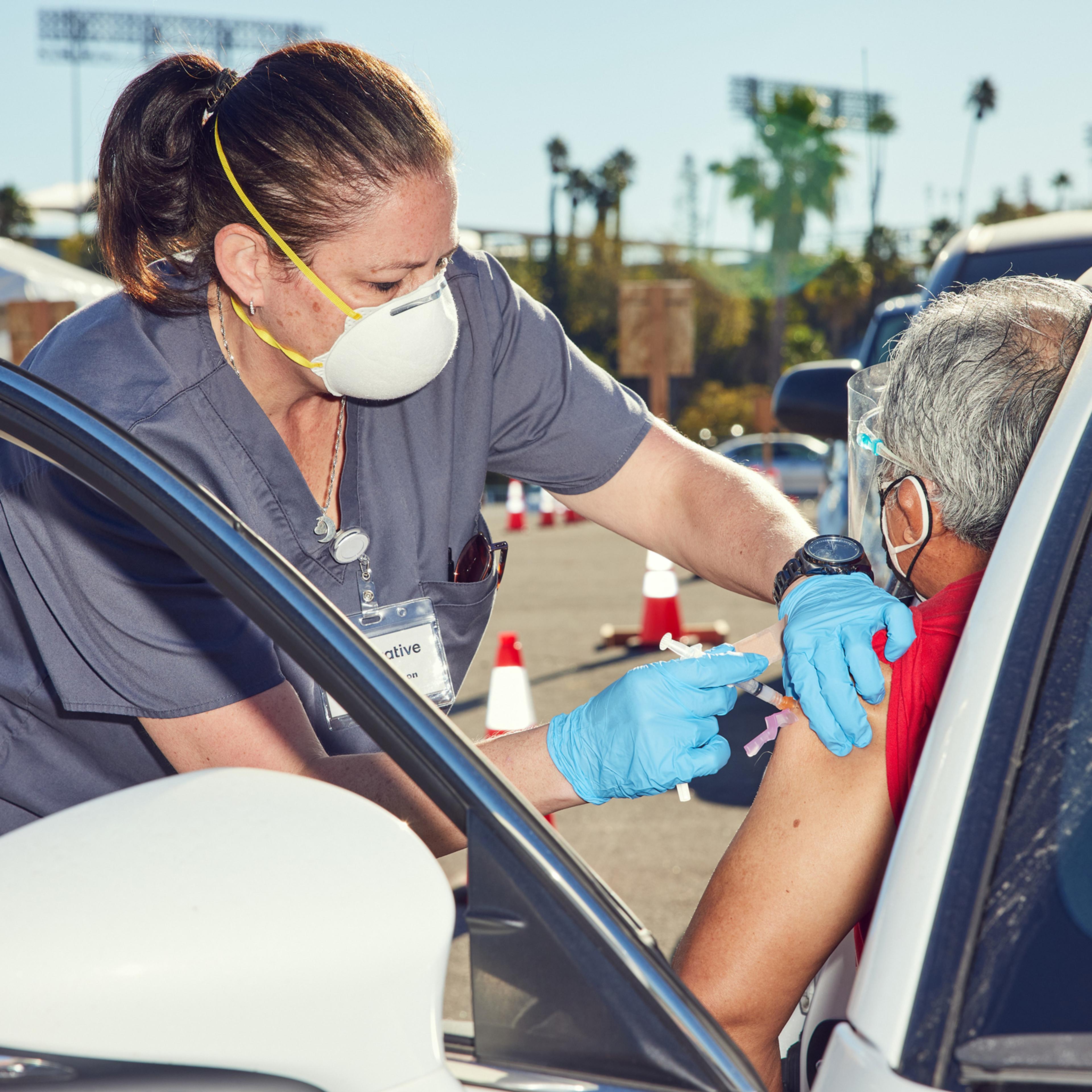 Stacey Manson, a nurse, gives a vaccination at Dodger Stadium in Los Angeles, Jan. 20, 2021. (Ryan Young/The New York Times)