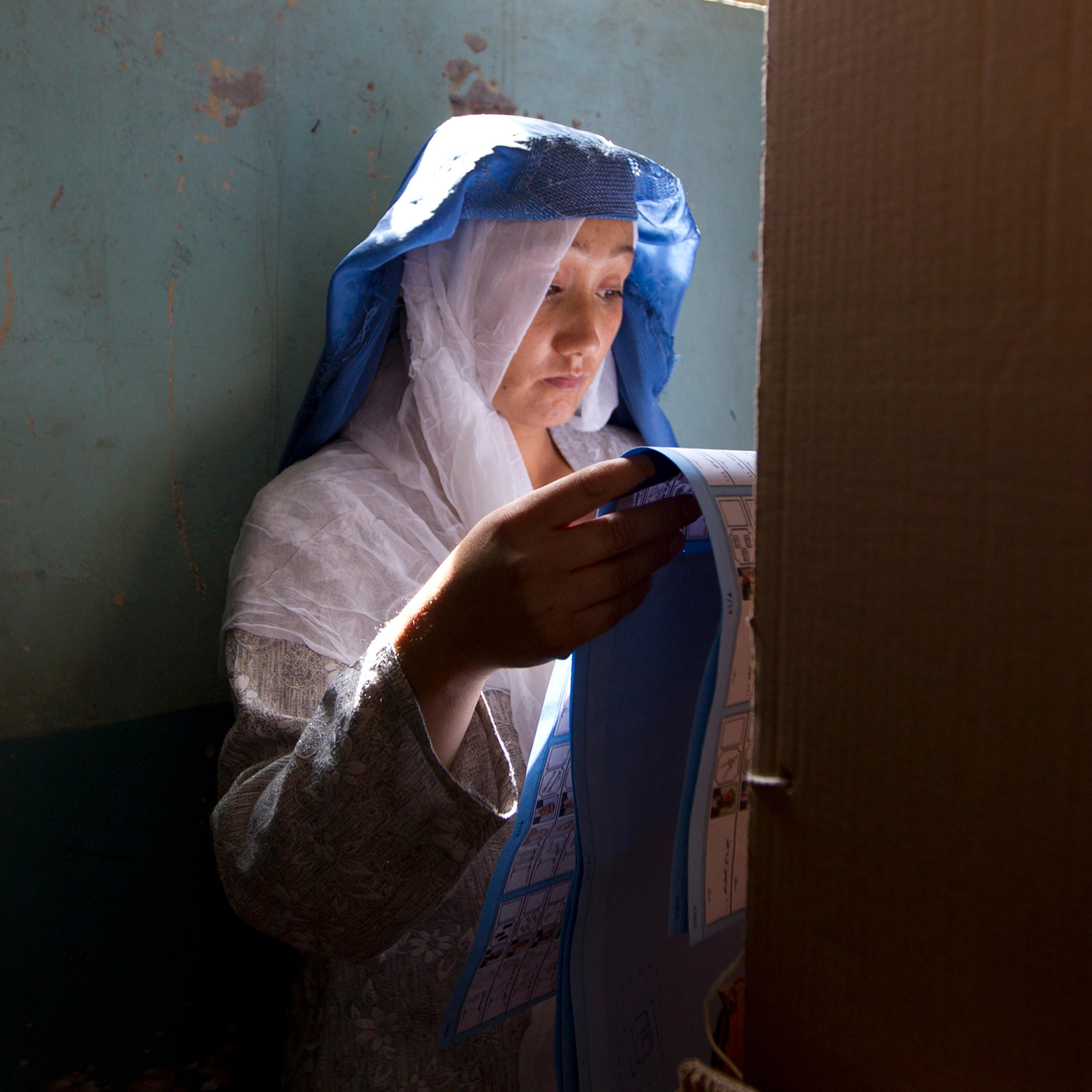 An Afghan woman searches for her candidate in a multiple-page ballot at a mosque in Kabul in September 2010. The Taliban had warned voters to boycott the polls and threatened violence to disturb the country's elections.