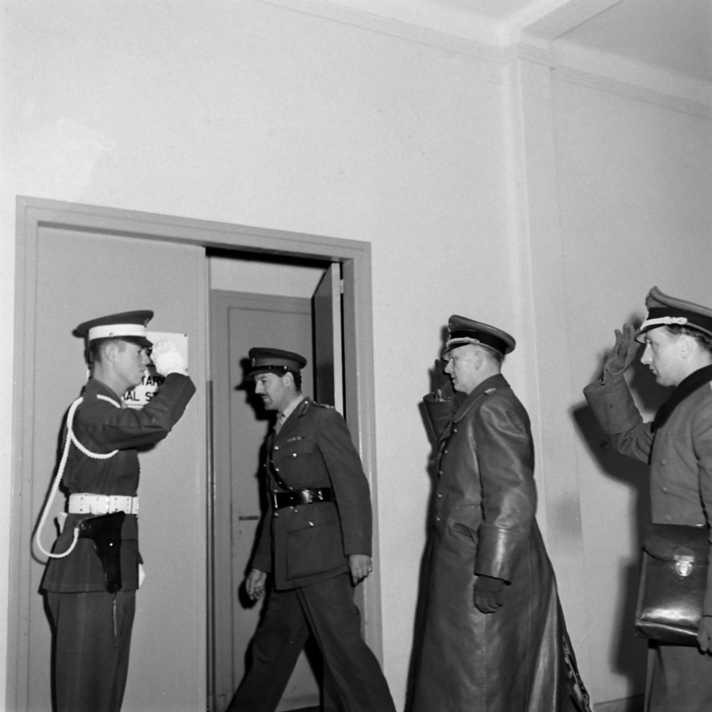 Nazi Chief of Staff Jodi (center), summoned by Admiral von Friedberg, arrived at SHAEF after 5 p.m. Sunday. With his aide, Major Oxenius (right), he is ushered into a side room.