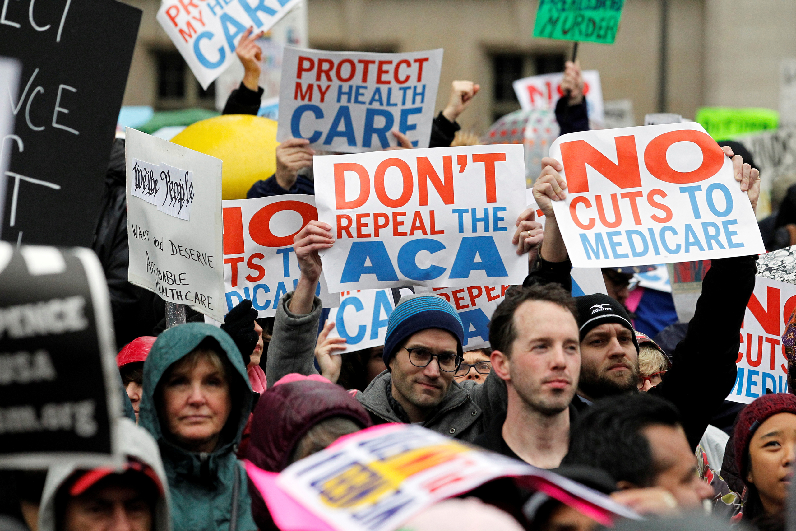 Demonstrators hold signs in support of the Affordable Care Act at a gathering before the start of a protest march near the hotel where House and Senate Republicans are attending a retreat, in Philadelphia, Pennsylvania, U.S. January 25, 2017. REUTERS/Tom